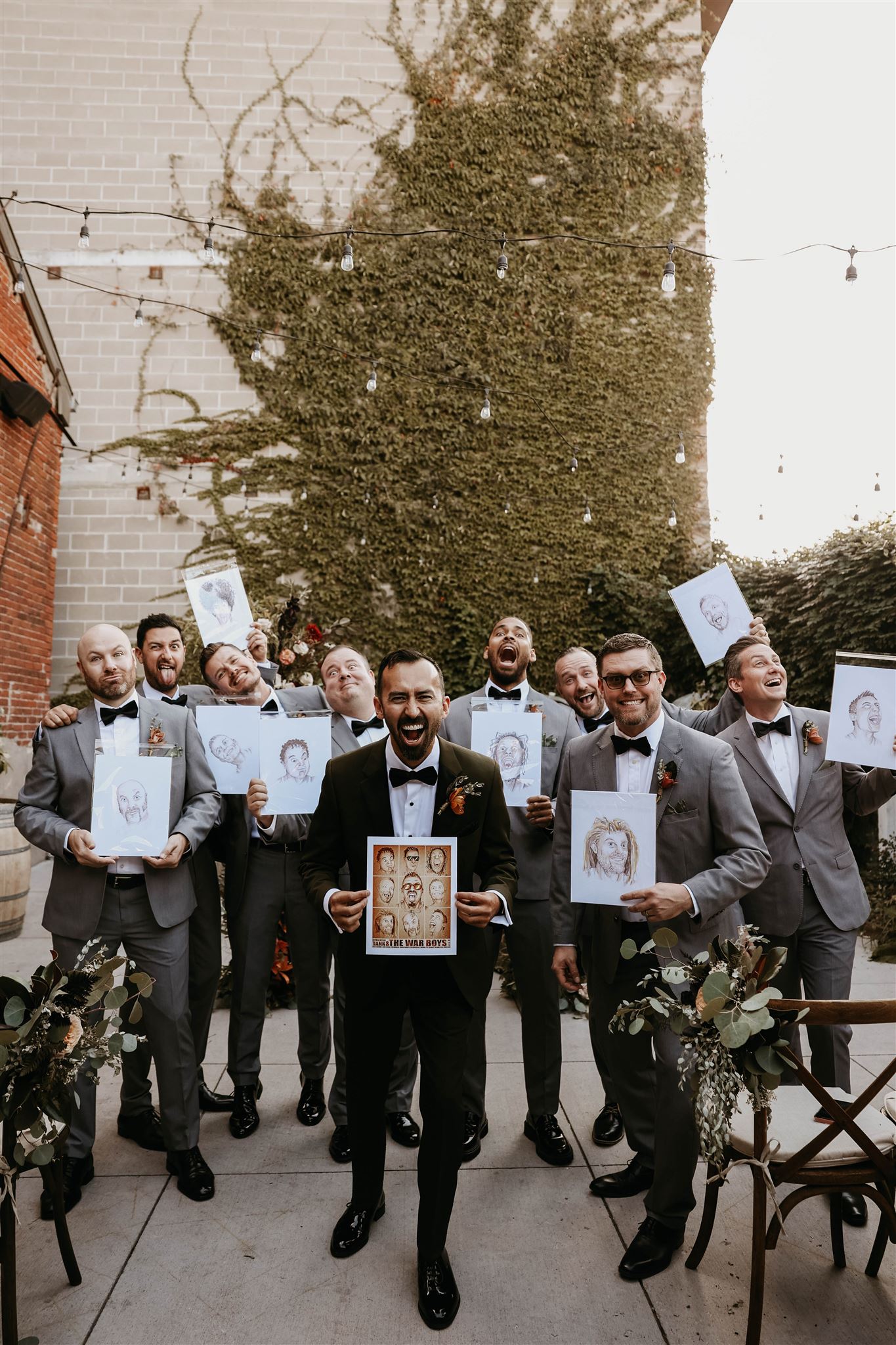 groom and groomsmen holding up portraits of themselves 