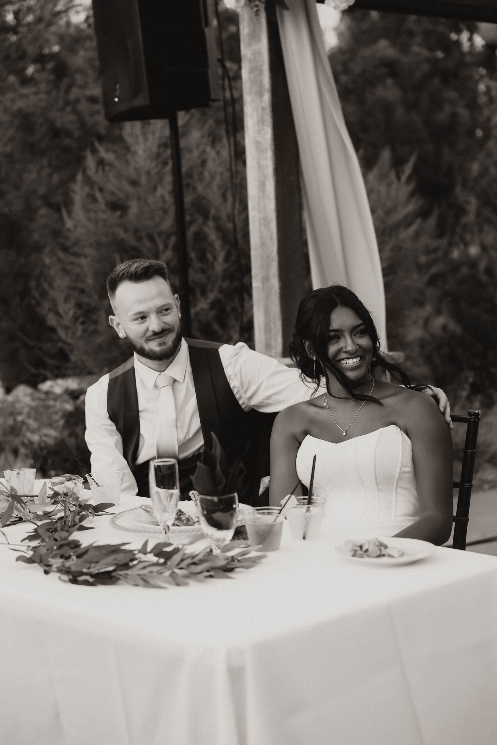 bridal couple at reception table smiling 