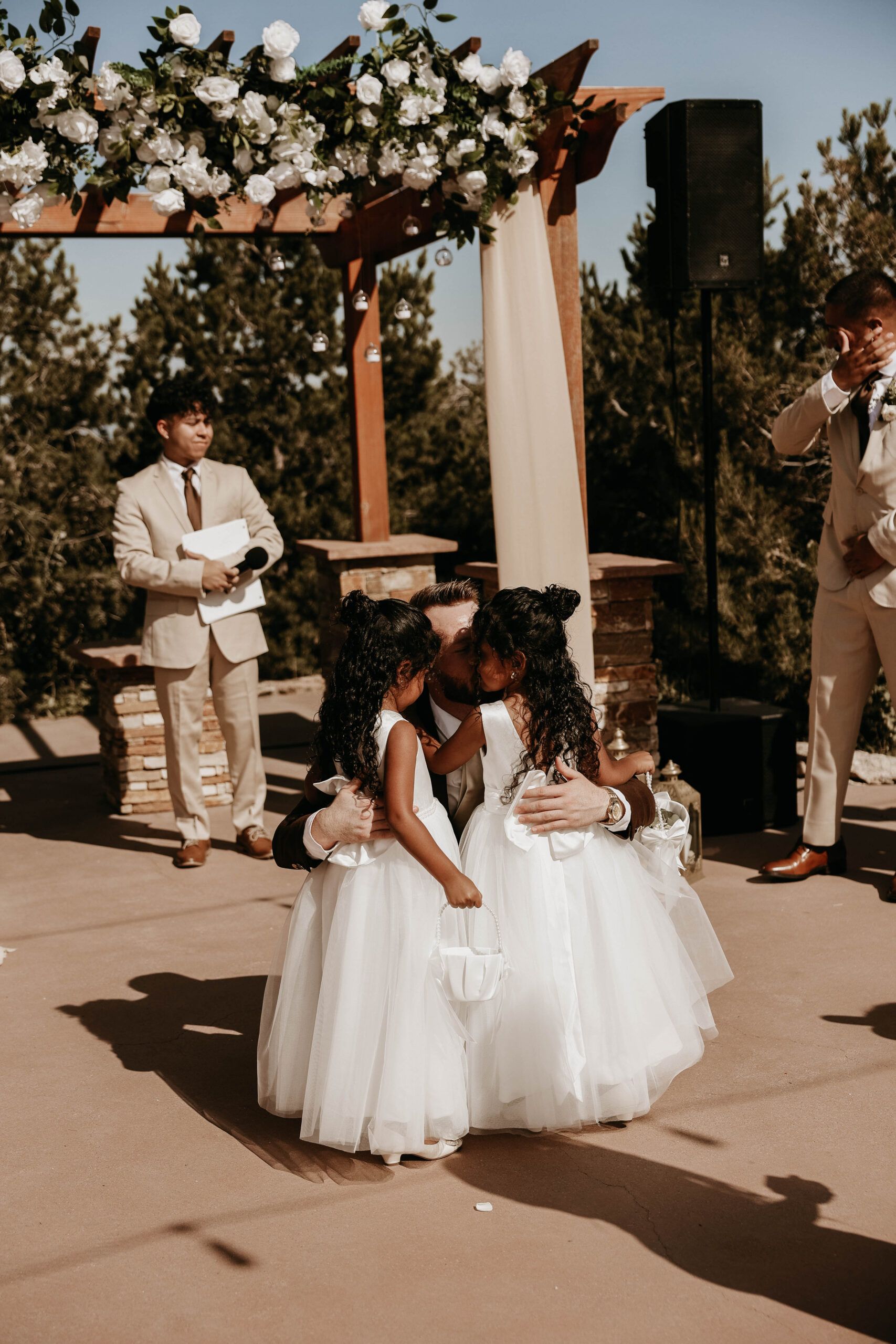 groom and daughters hugging at end of the aisle 