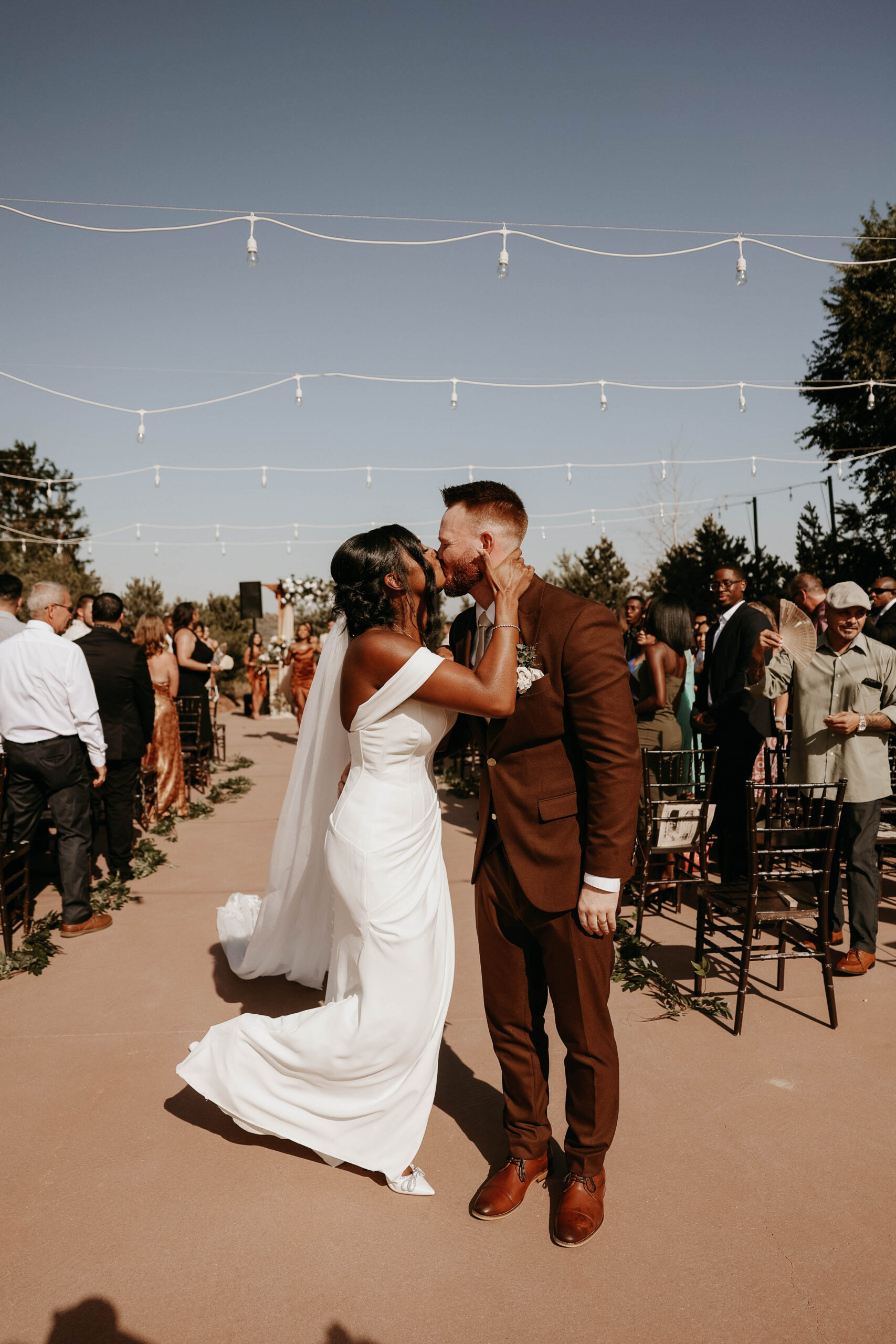 bridal couple kissing at the end of the aisle at outdoor wedding in Colorado