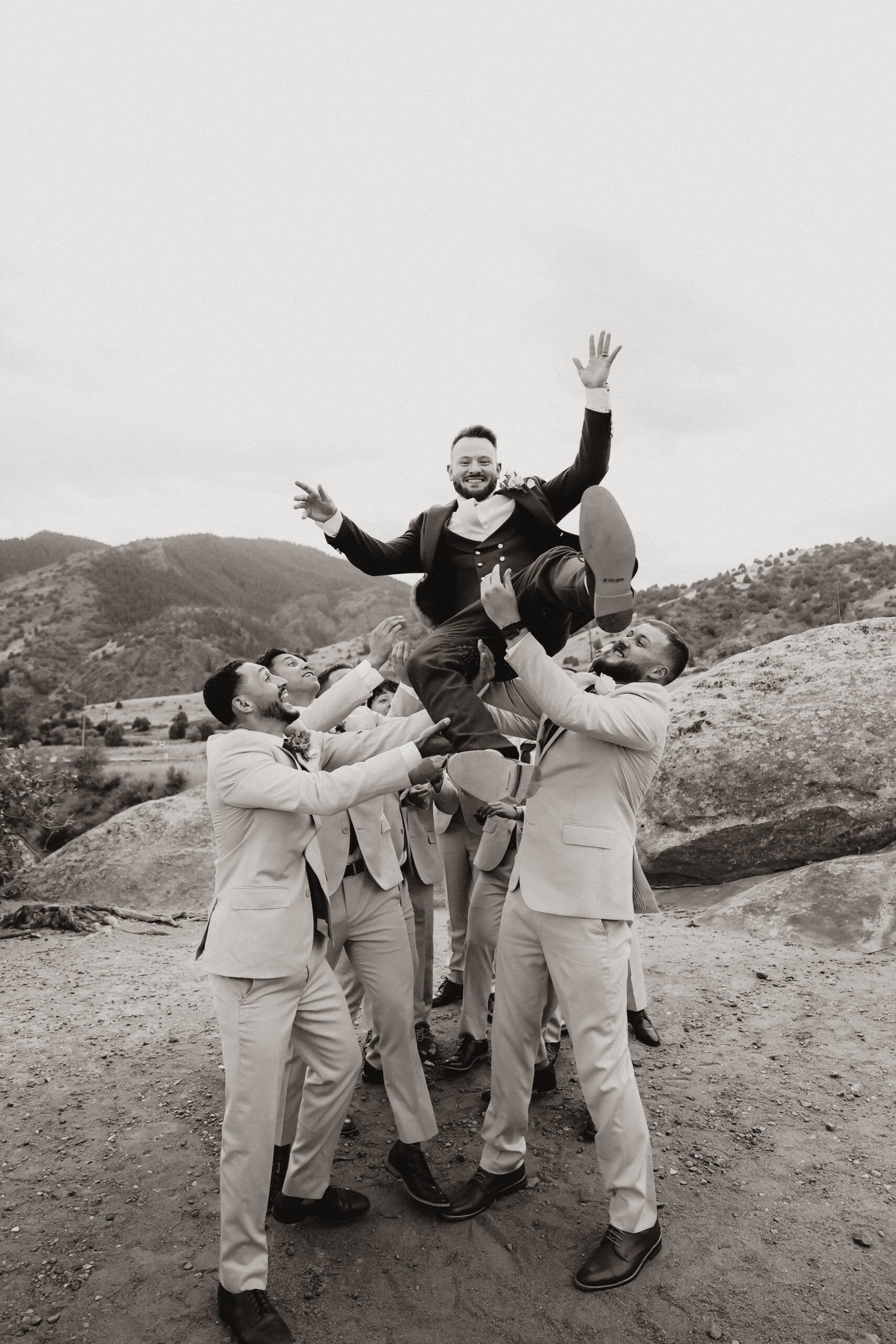 black and white of groomsmen holding up the groom 