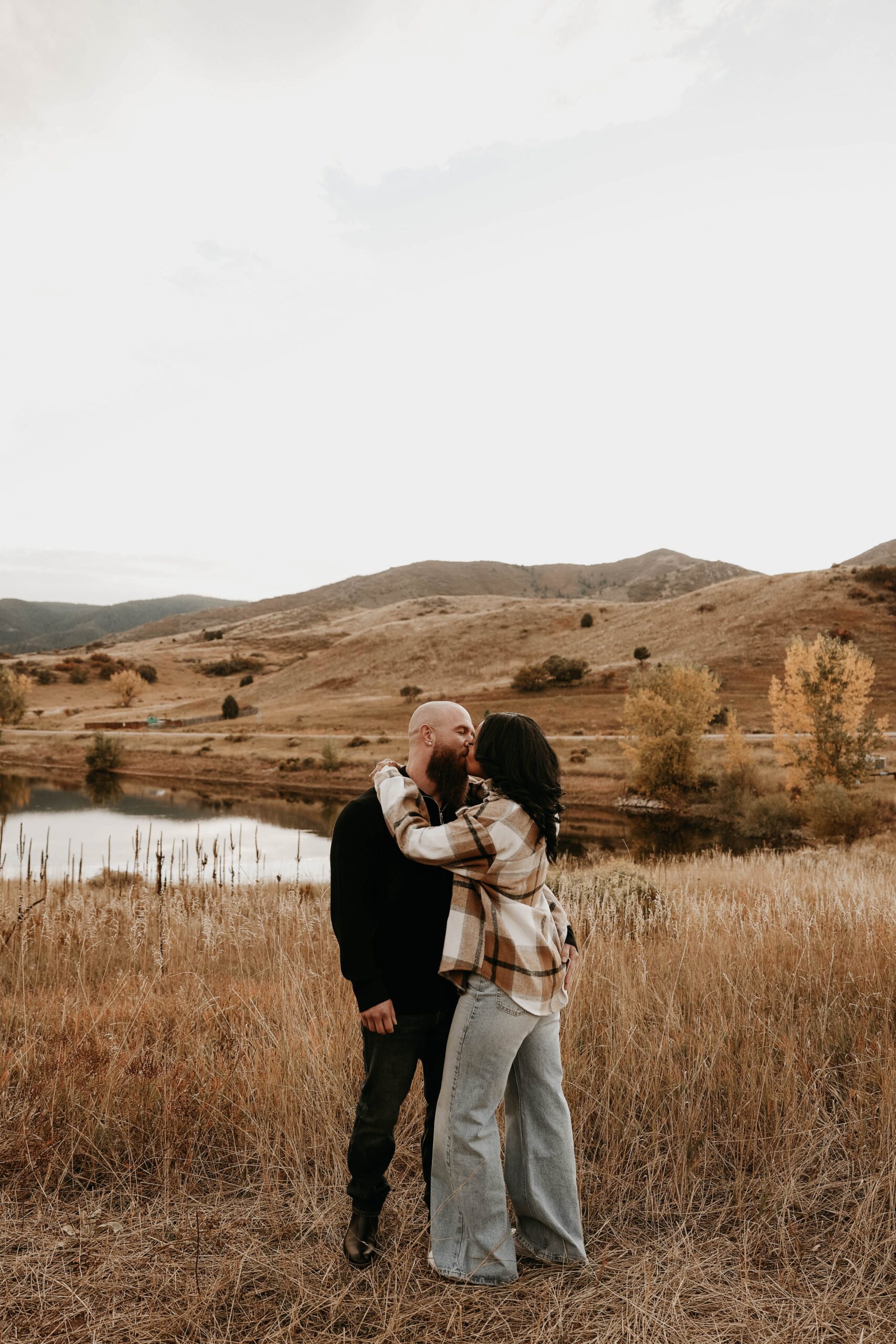 engaged couple kissing in dry grass in colorado for their engagement photos 