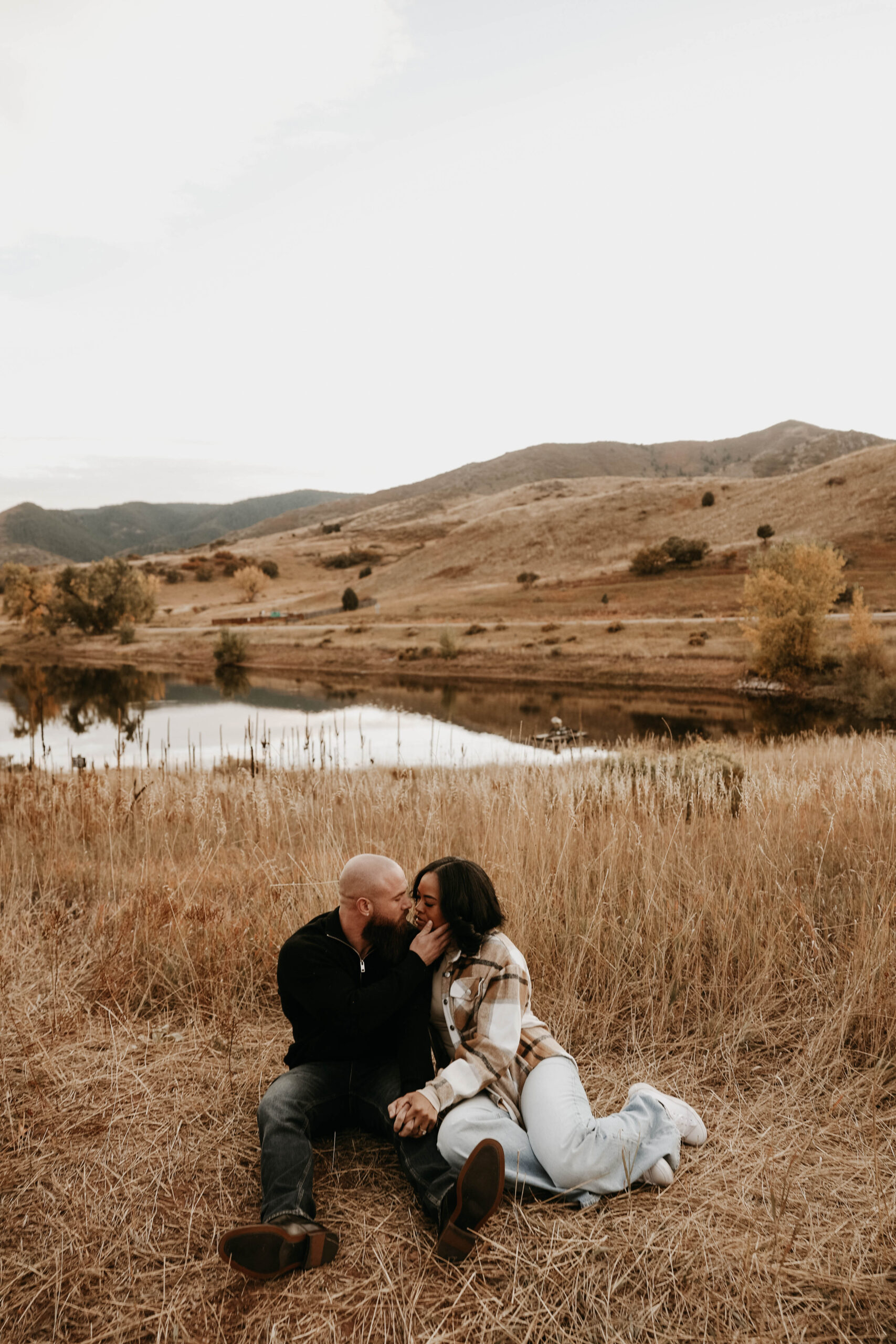 photographers picture of newly engaged couple sitting and kissing during their engagement photos 