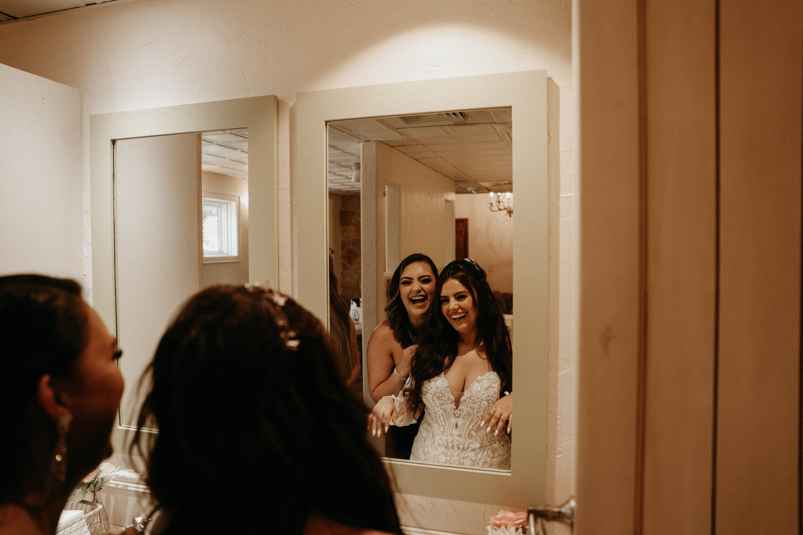 bride and friend looking in the mirror and laughing 