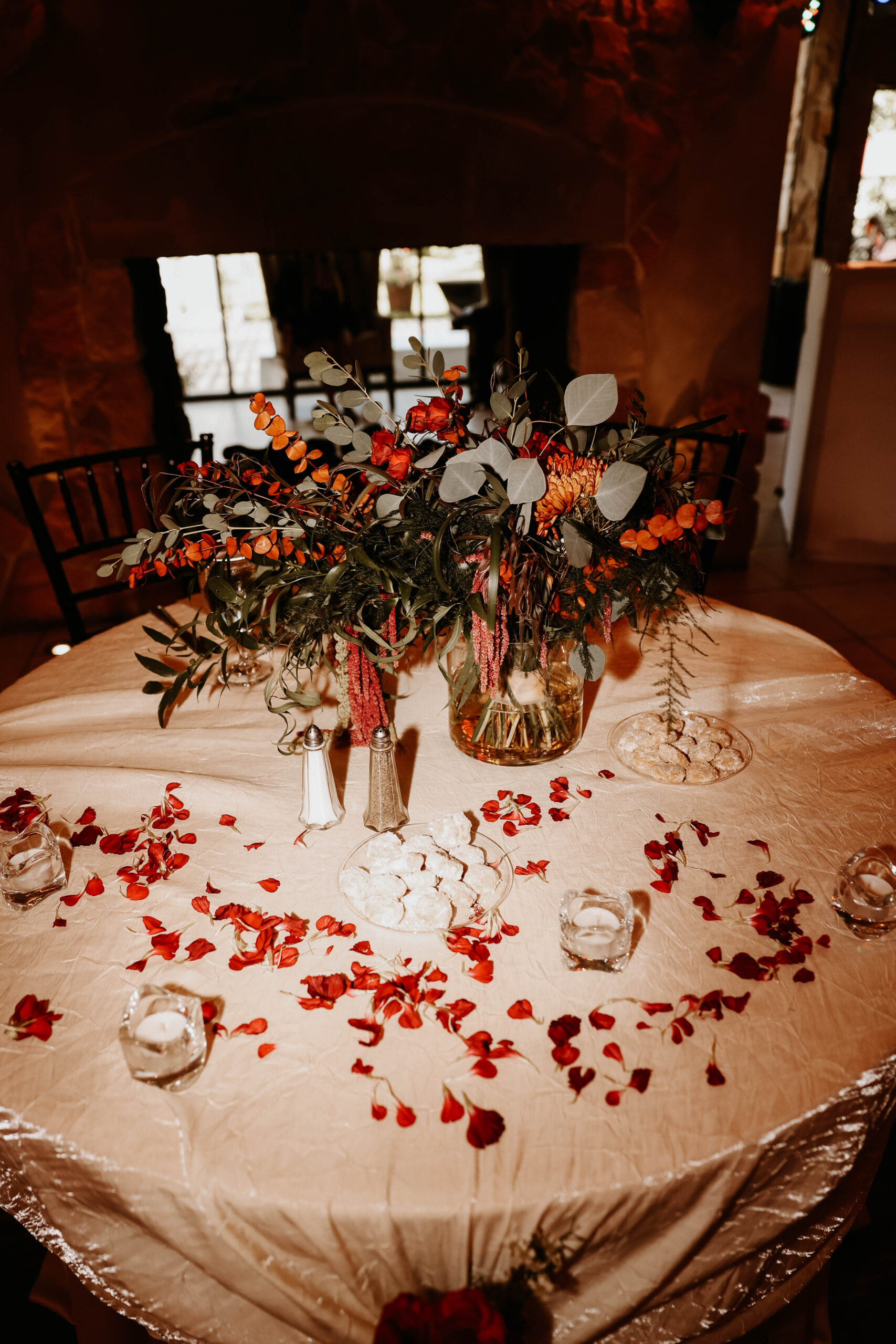 wedding reception table decor with red flower petals on the table