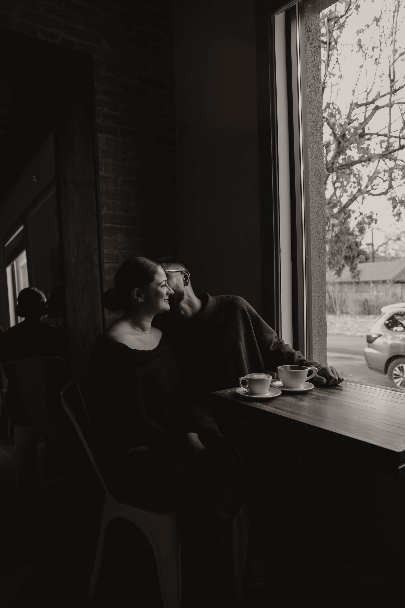 engaged couple at their engagement photo location, a coffee shop, sitting at a table smiling 