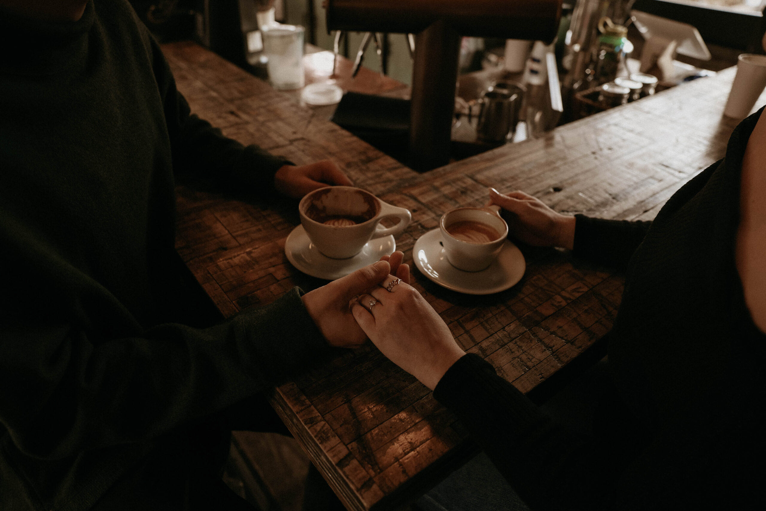 couple holding hands with their coffee at the bar