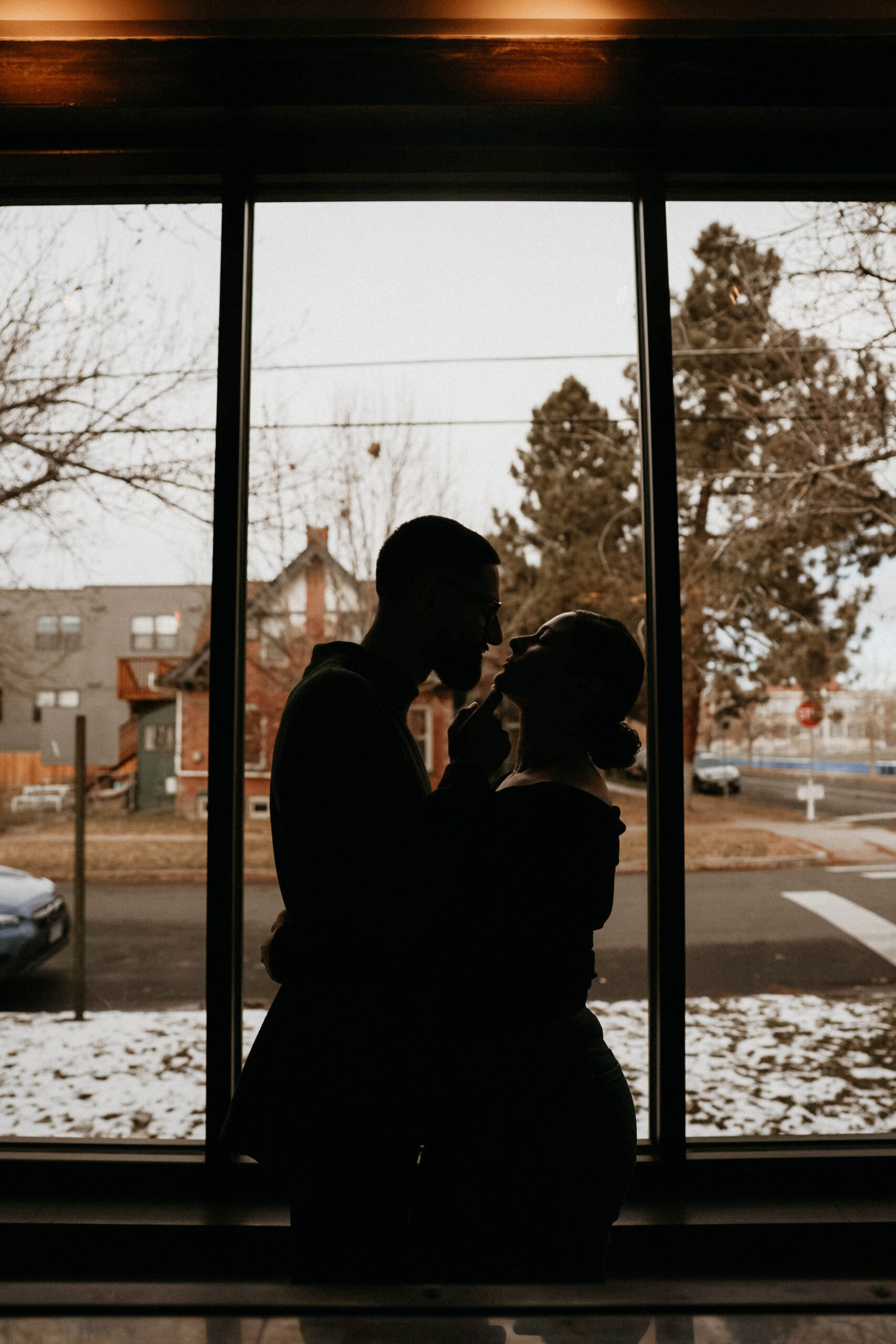engaged couple standing by the window in the coffee shop about to kiss