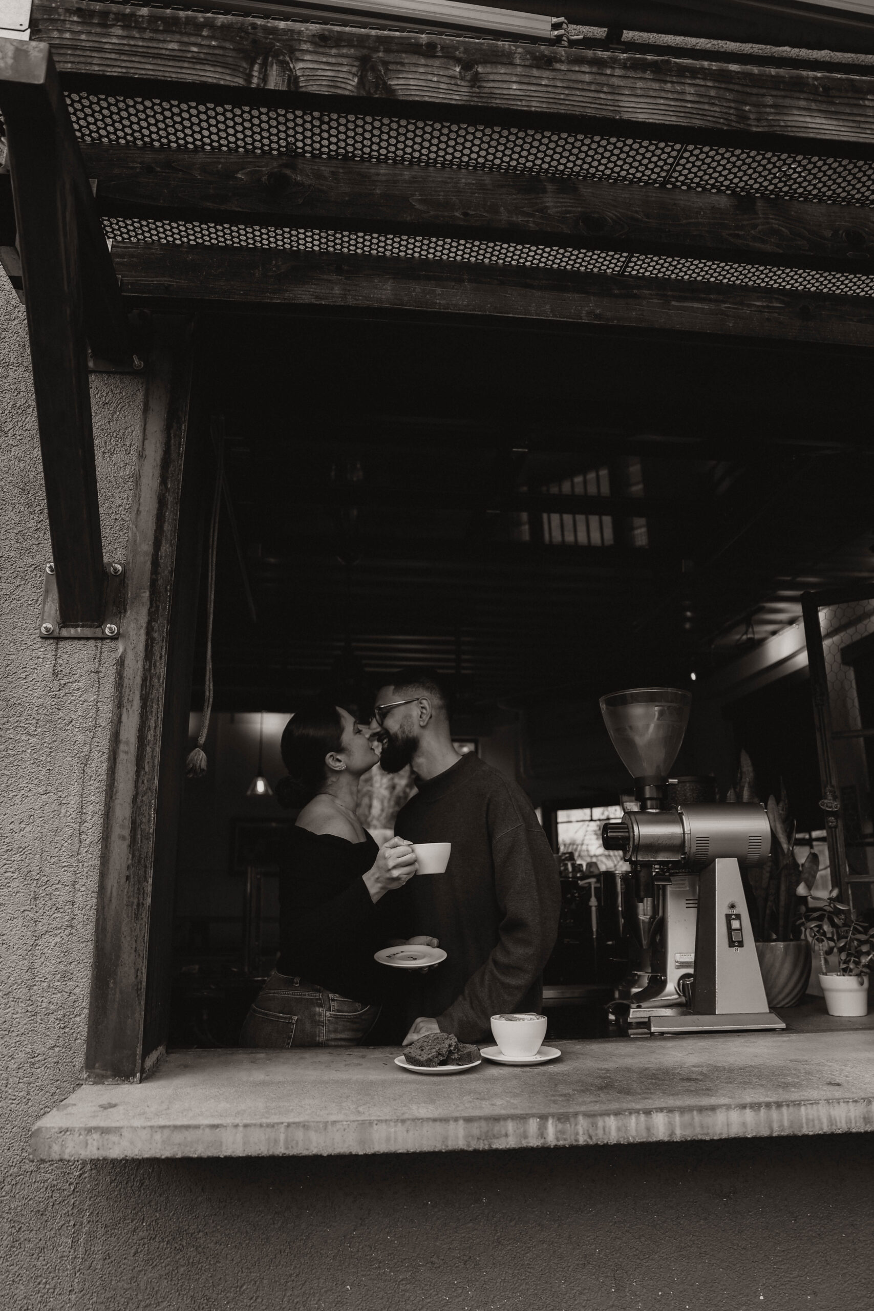 engaged couple kissing in the coffee shop window 