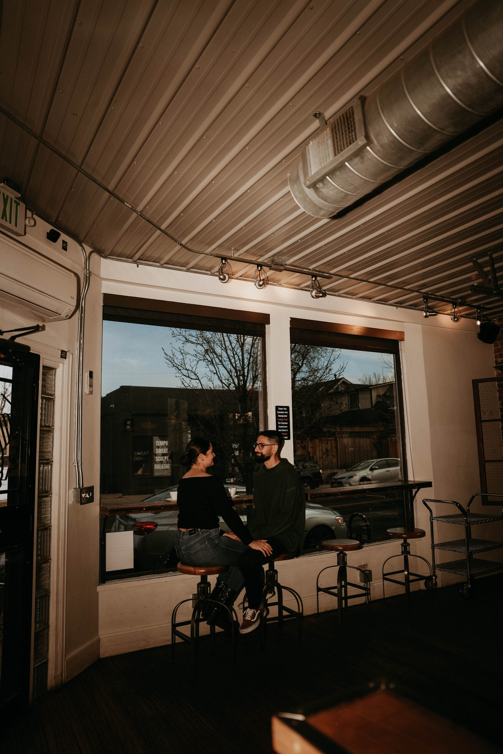flash photo of couple sitting at window bar of coffee shop during engagement photos 