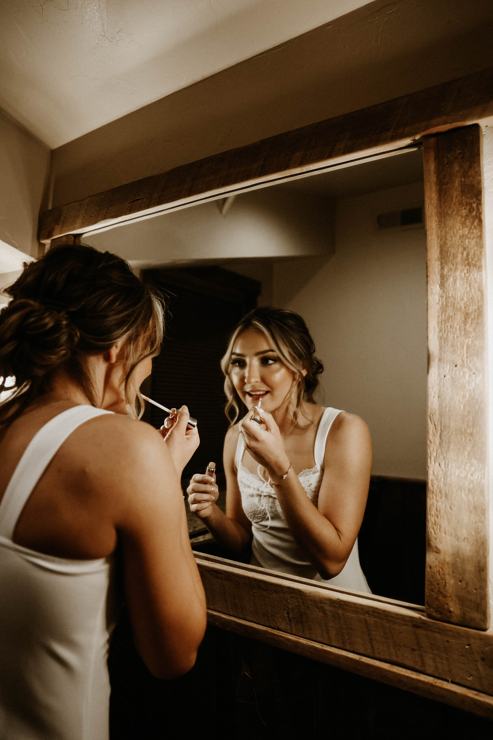 bride putting lipstick on in the mirror 