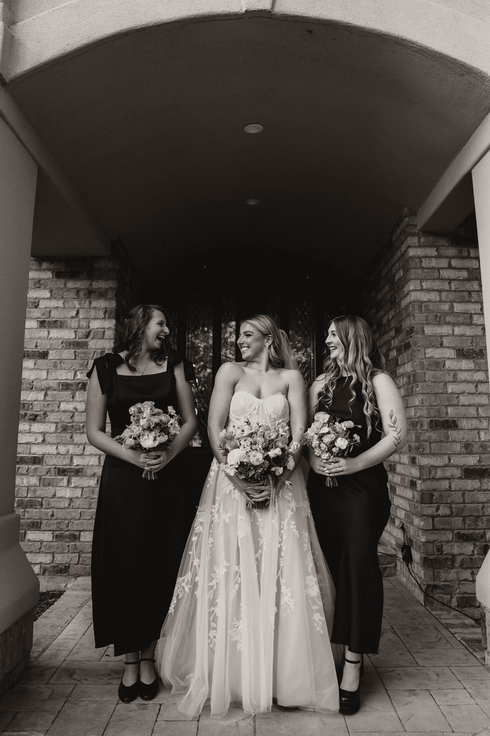 bride and bridesmaids looking at each other smiling 