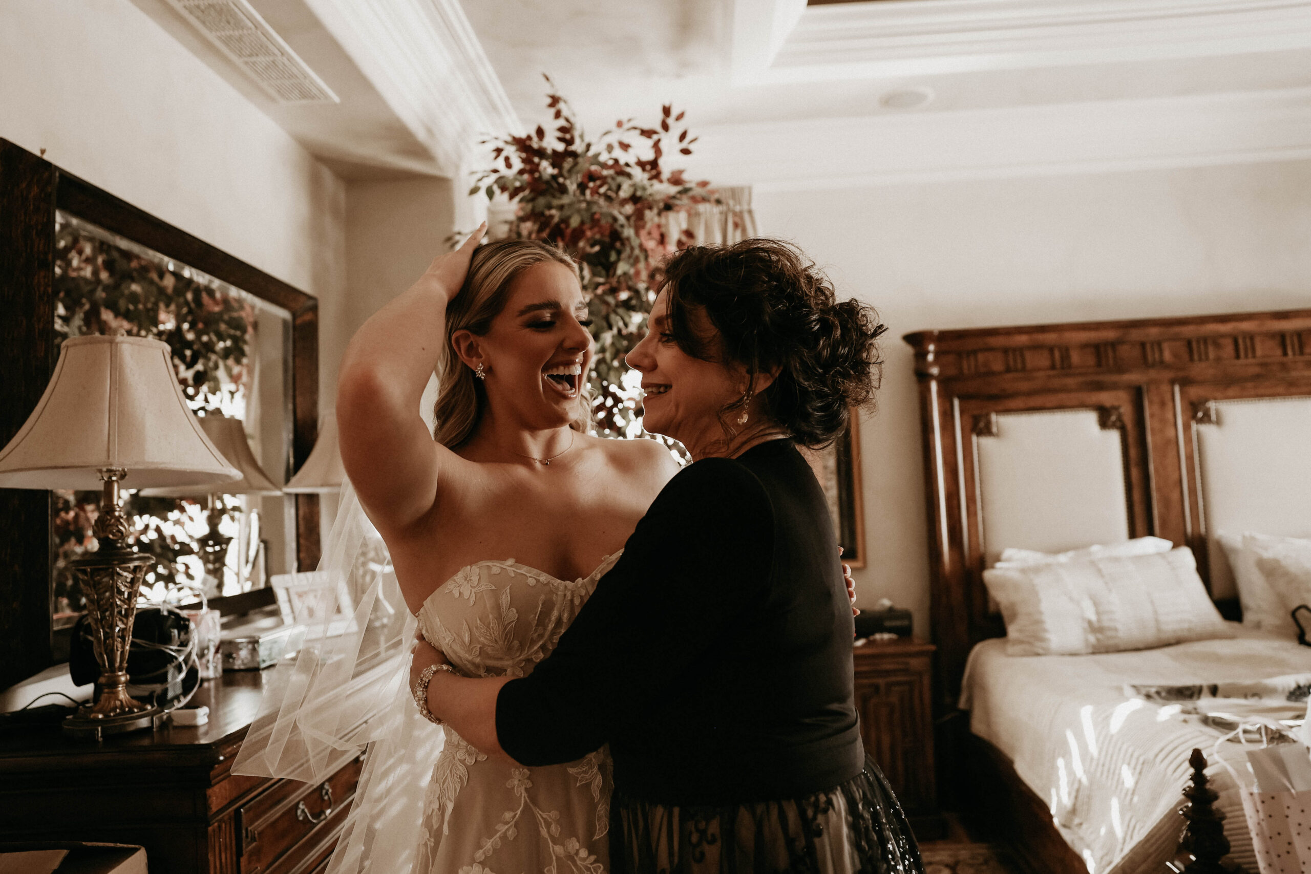 bride and her mother laughing while she gets ready 