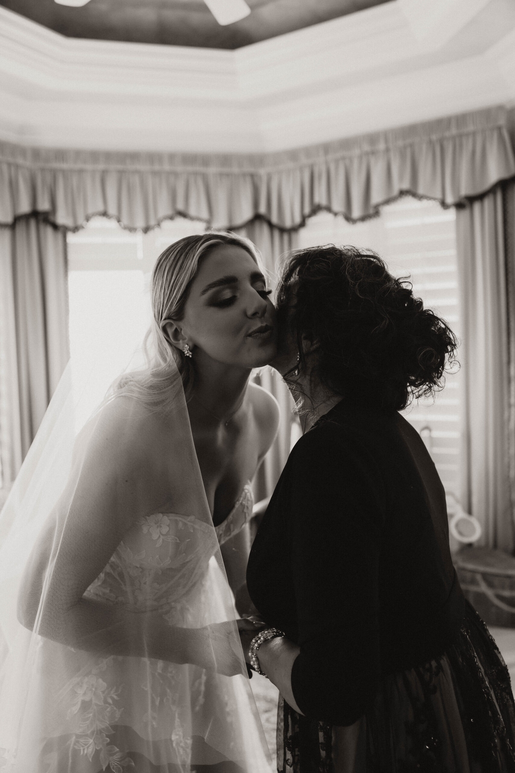 bride and mother kissing each other's cheek