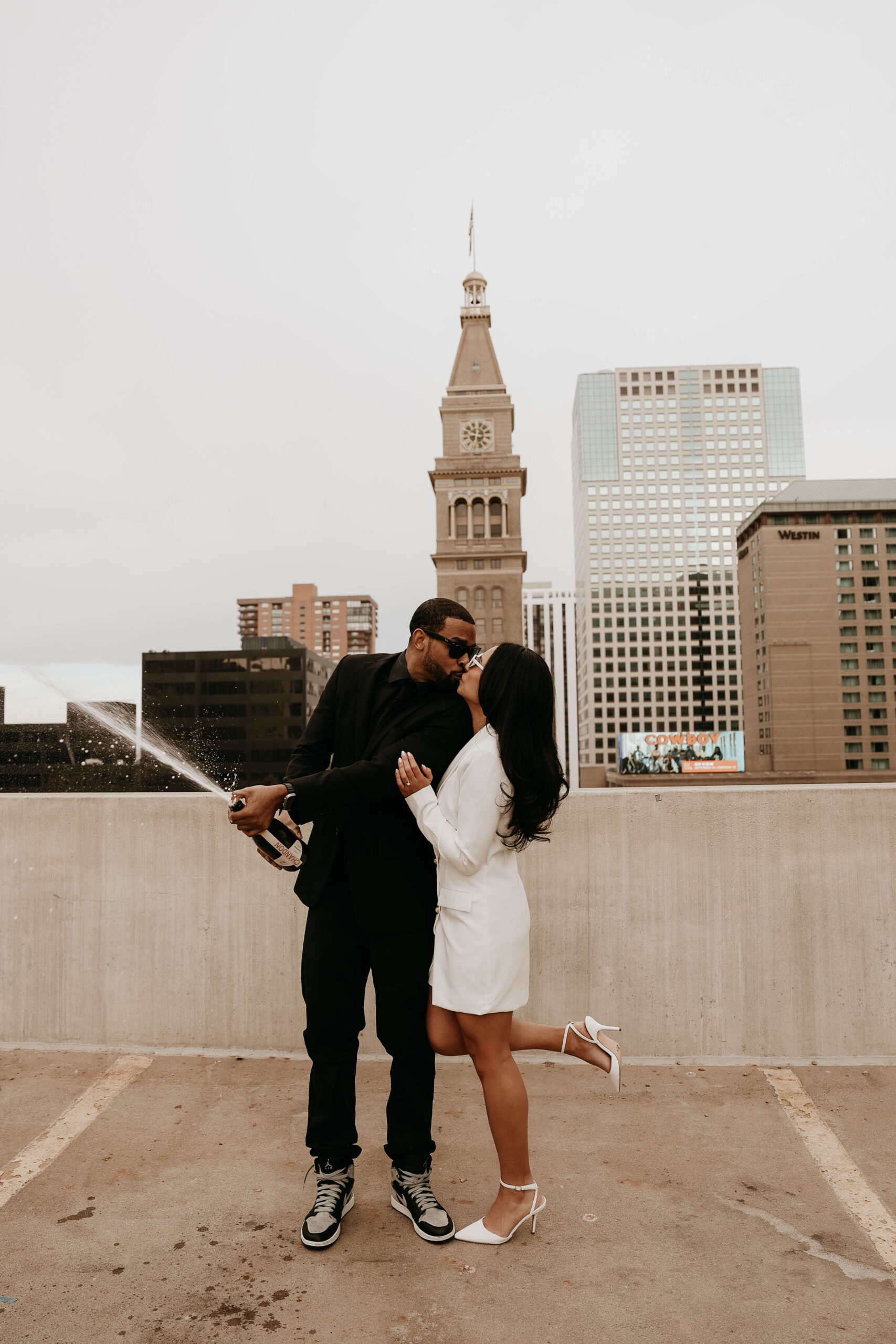 newly engaged couple popping champagne on a rooftop in downtown Denver 