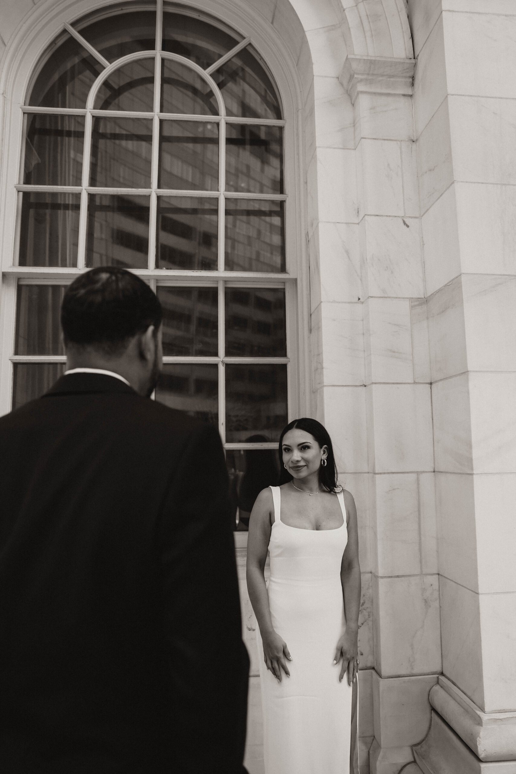 groom to be standing in front of bride to be while she looks at him 
