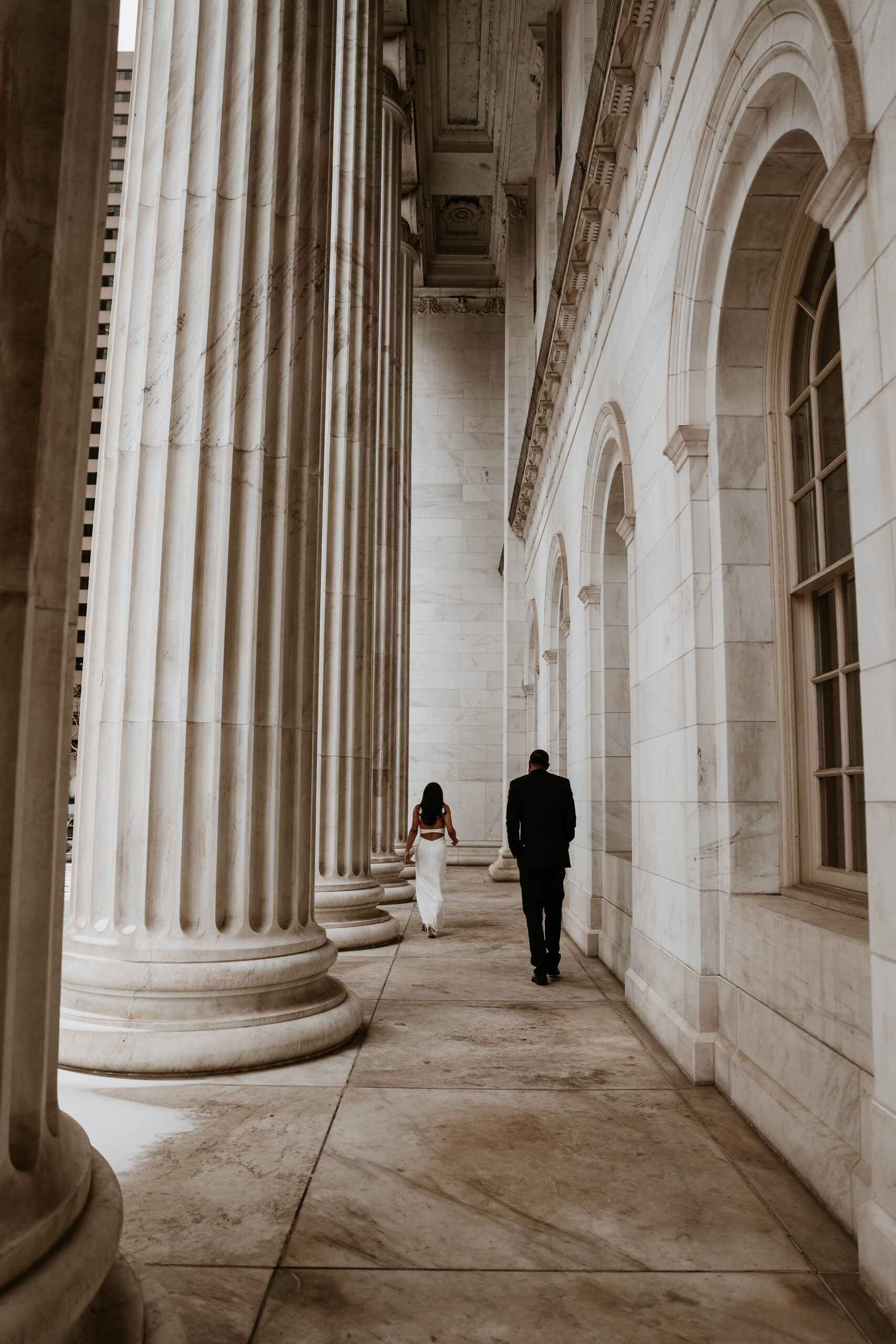 newly engaged couple walking by the giant white pillars of the courthouse, bringing their unique engagement shoot ideas to life 
