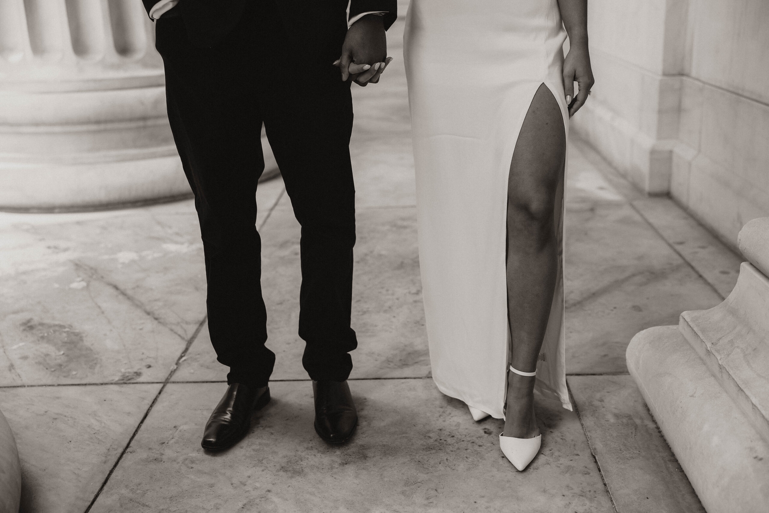 black and white of the newly engaged  couple holding hands from the waist down 