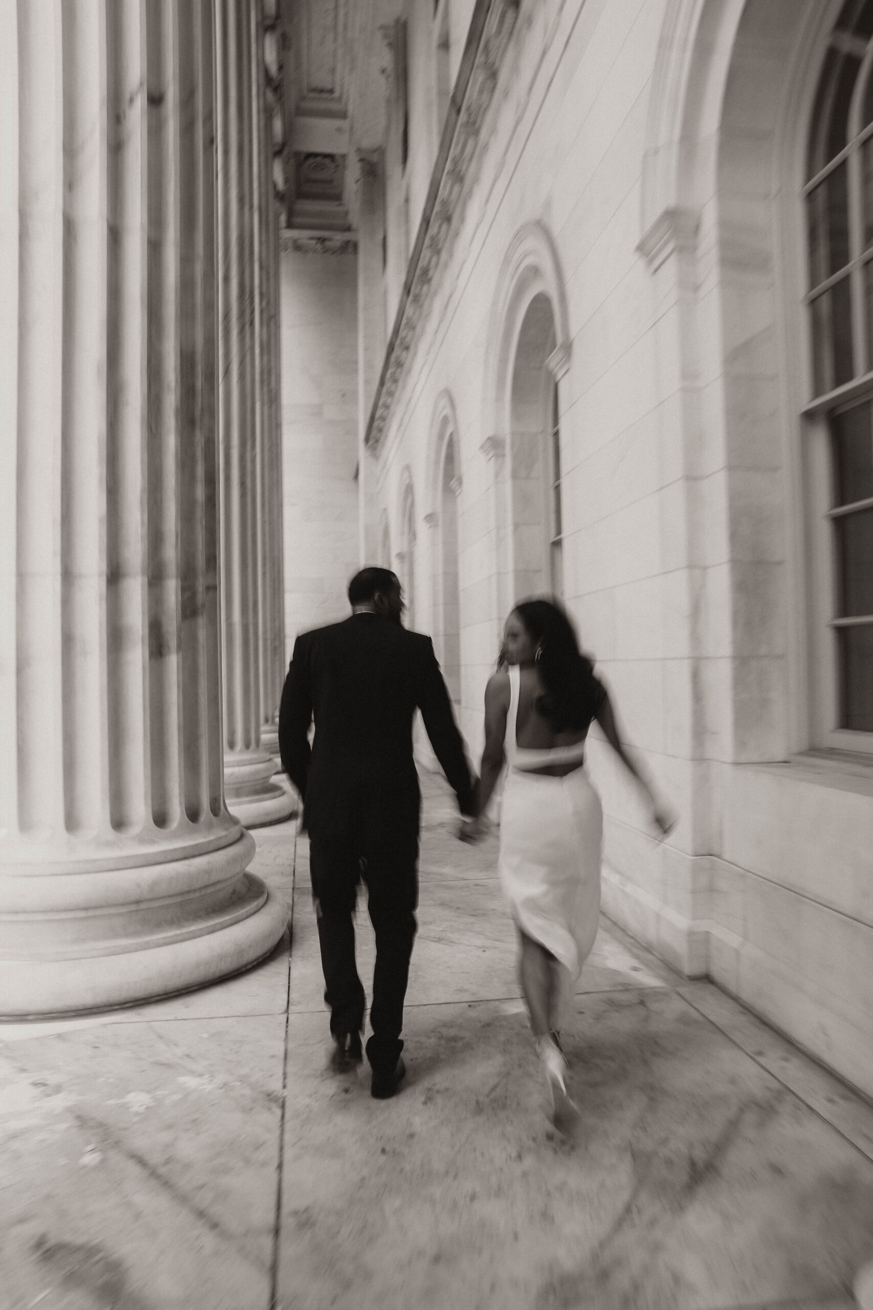 blurry photo of engaged couple holding hands and running from the camera 