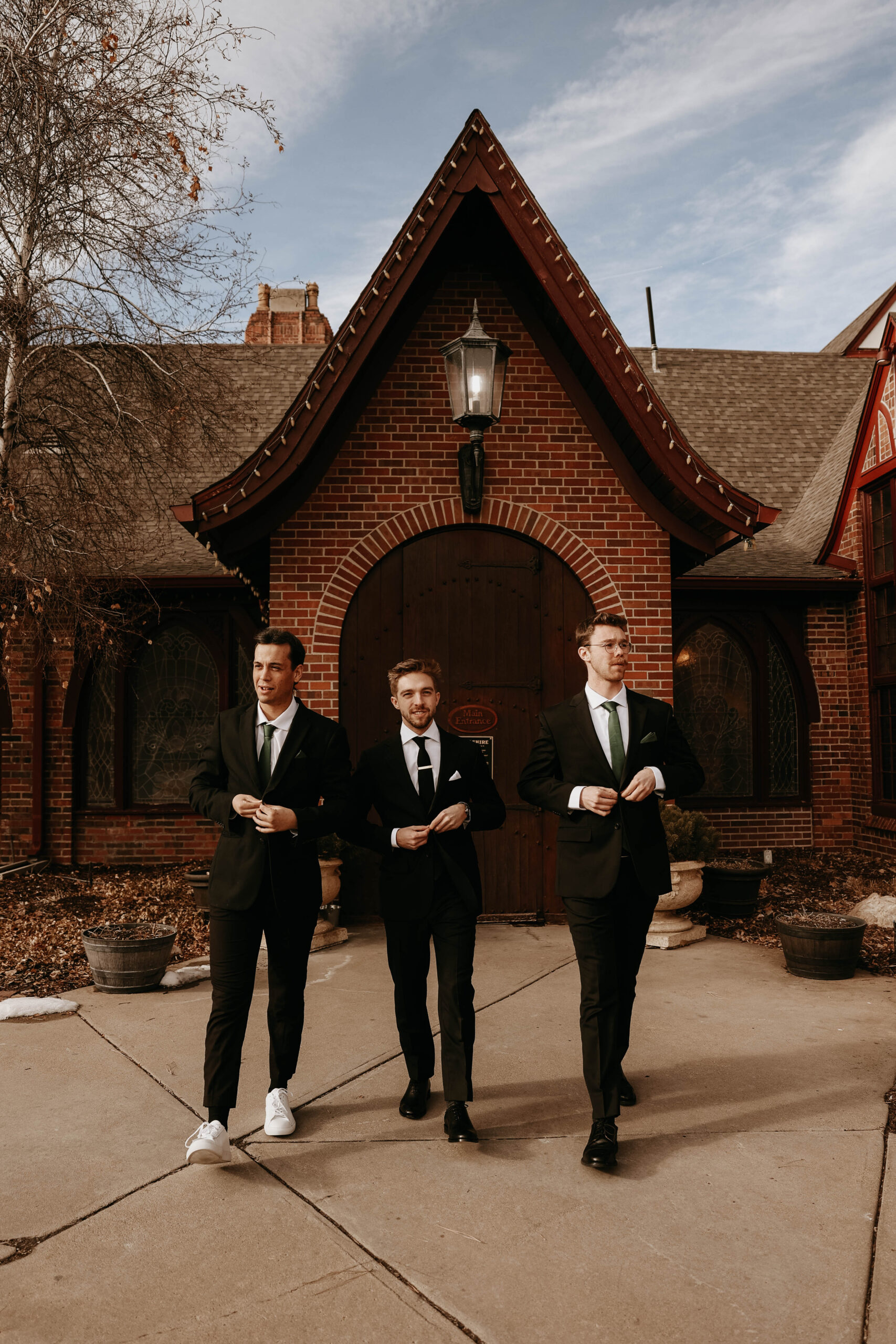 groom and groomsmen walking and buttoning their vests 