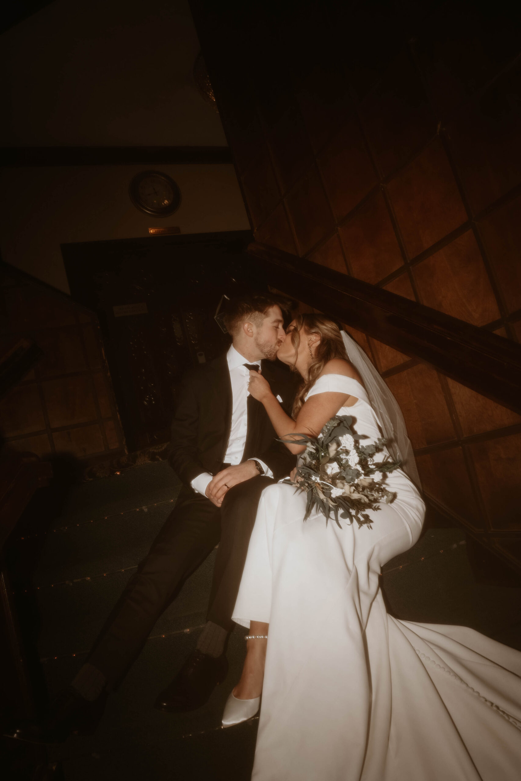 bride and groom flash photo of them kissing on the stairs 