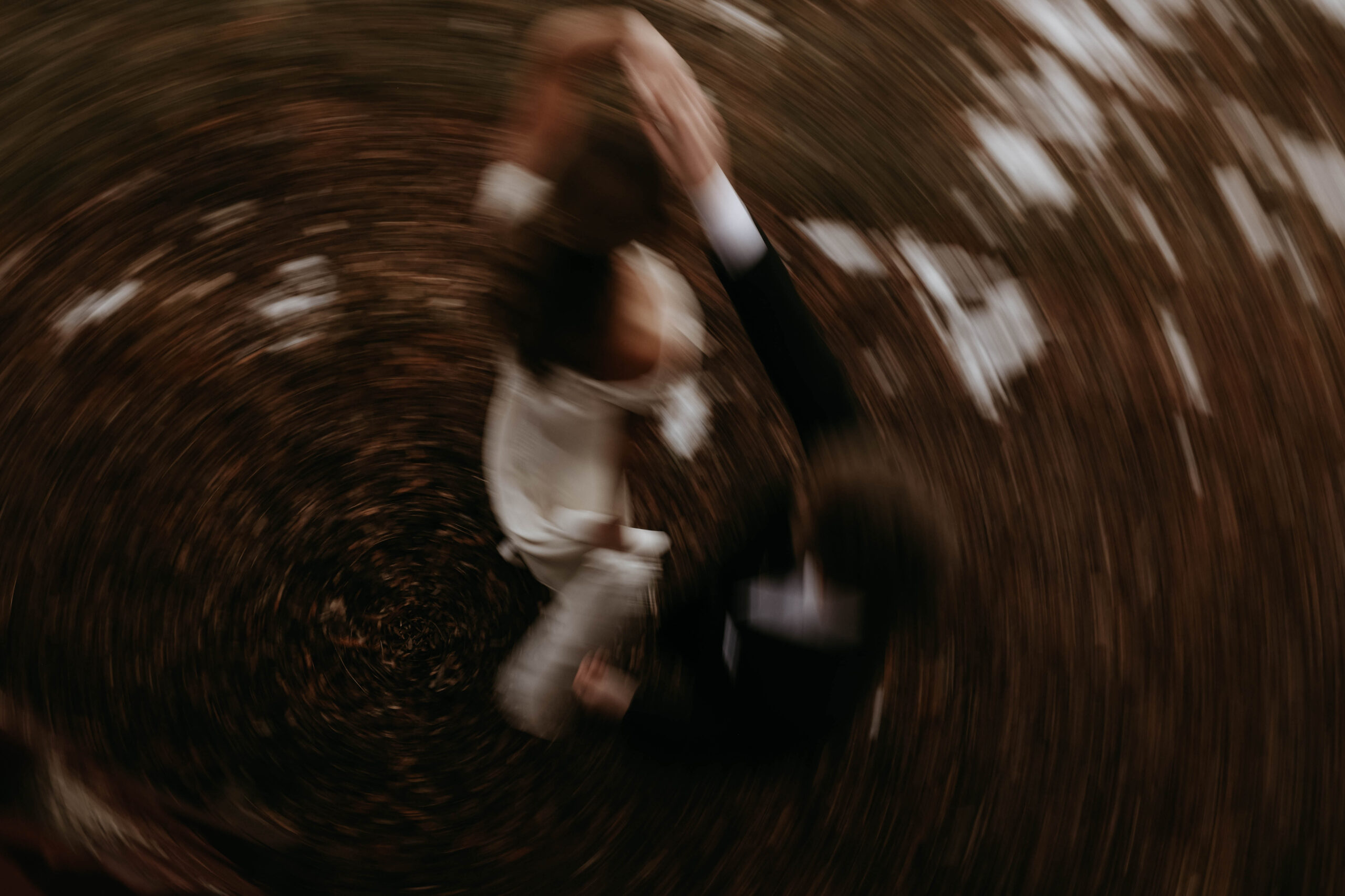 blurry aesthetic photo of groom spinning bride 