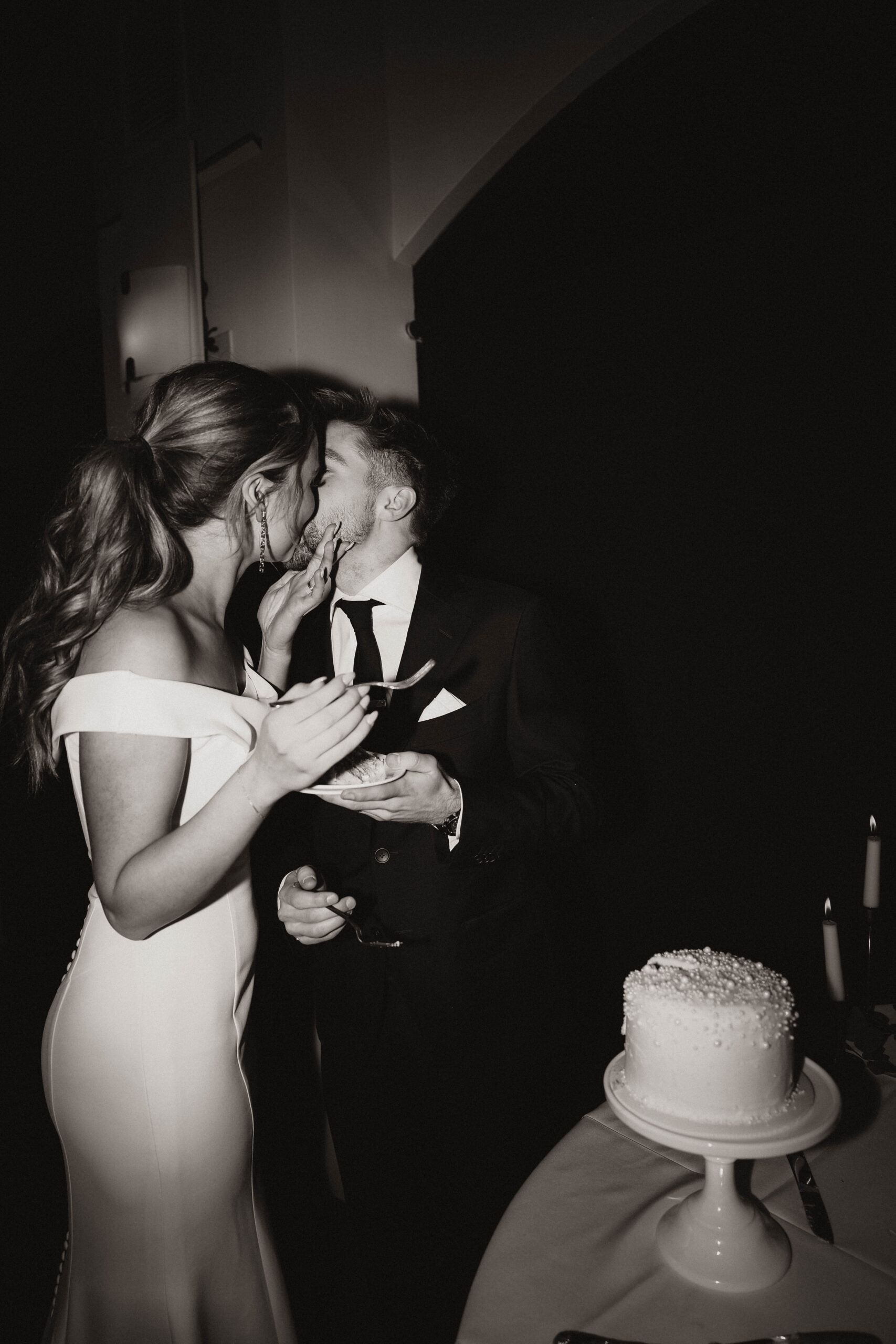 bride and groom kissing as they eat cake 