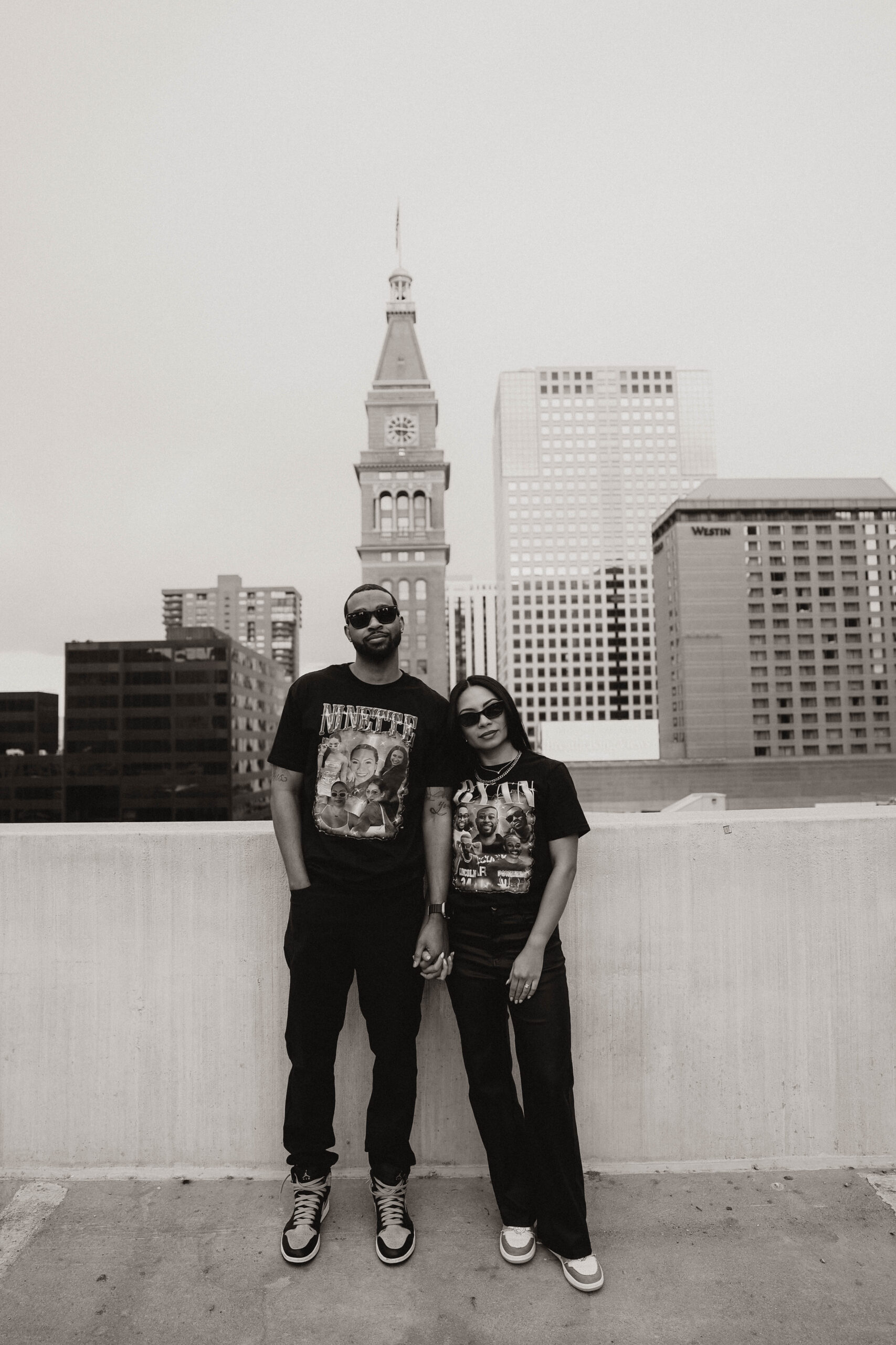 newly engaged couple in street wear on a rooftop wearing sun glasses expressing their unique engagement shoot ideas