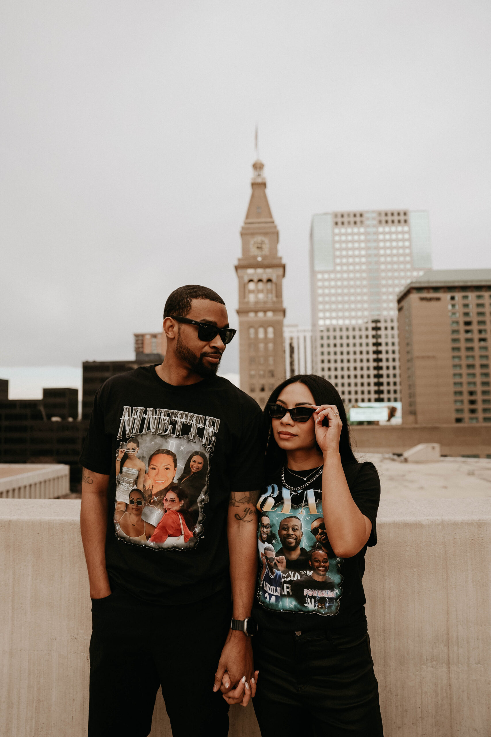 newly engaged couple on a rooftop with glasses on expressing their unique engagement shoot ideas