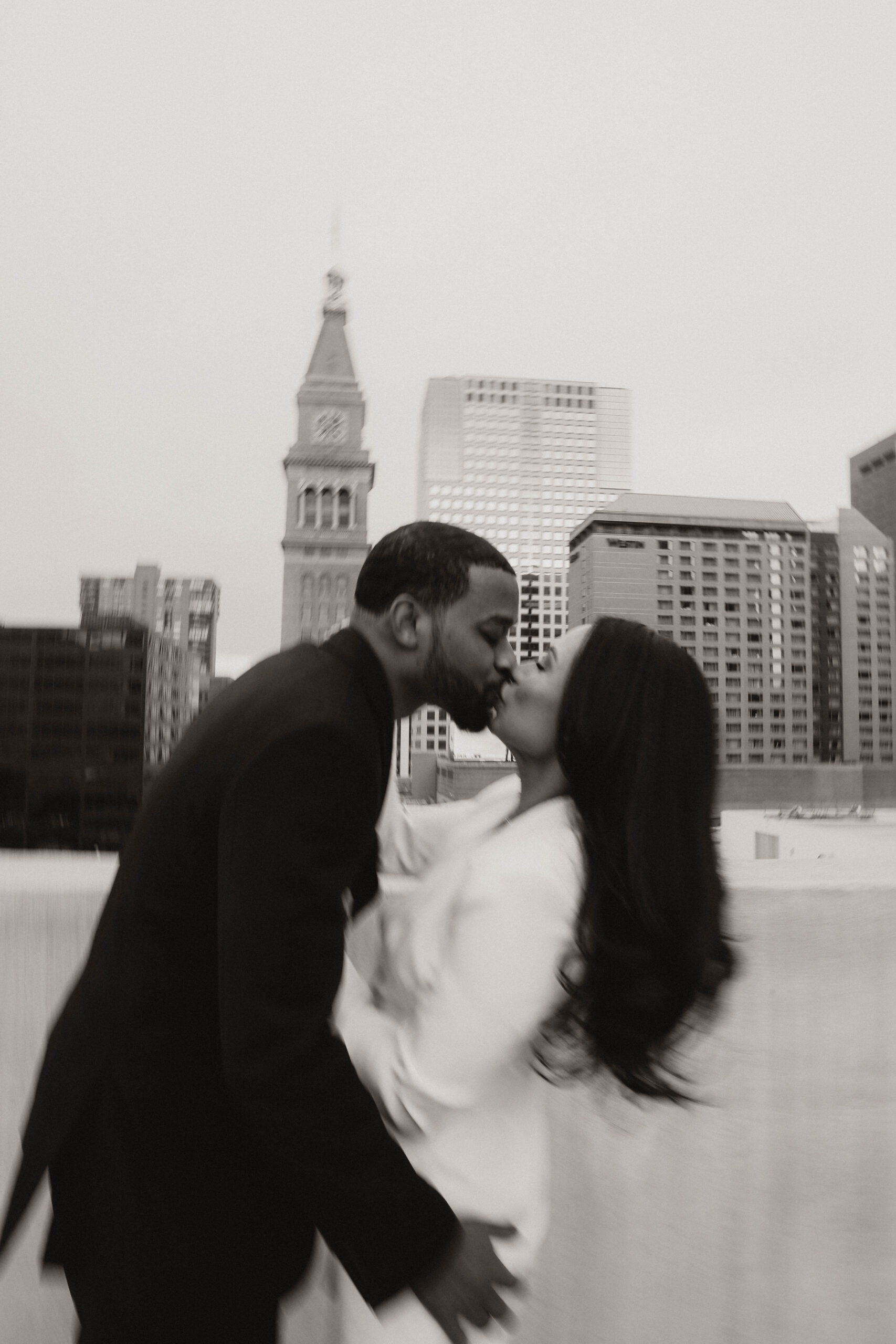 blurry photo of engaged couple kissing on a rooftop 
