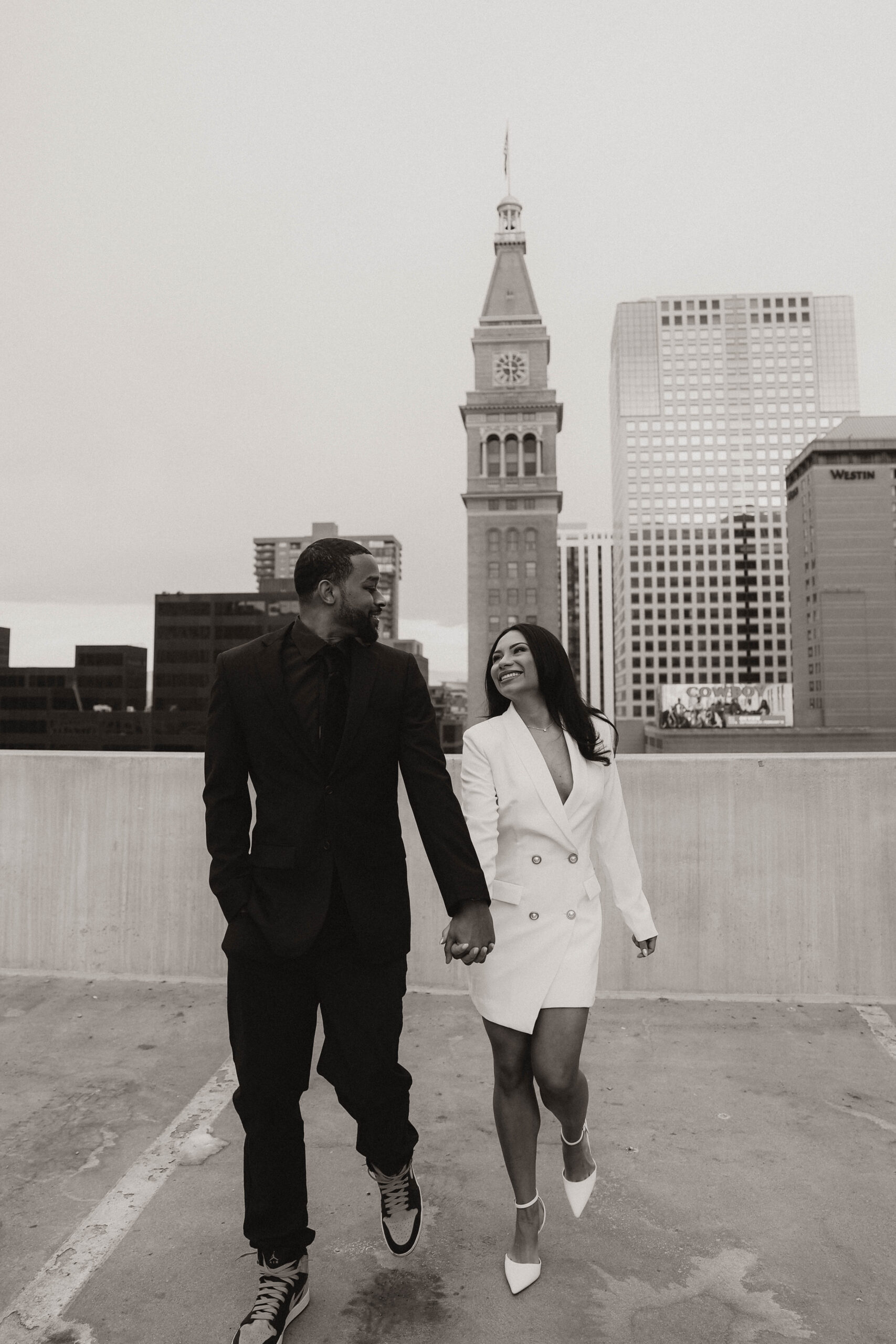 engaged couple in formal wear on a rooftop walking together expressing their unique engagement shoot ideas