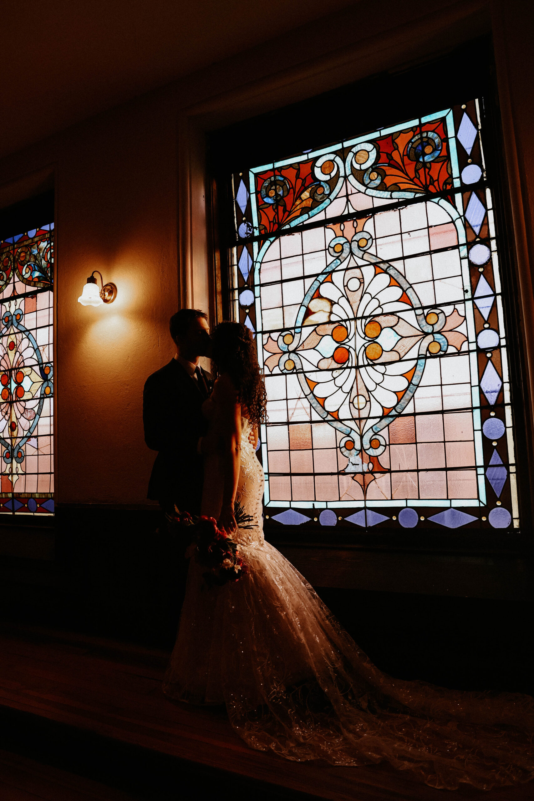 bride and groom portrait by a stained glass window 