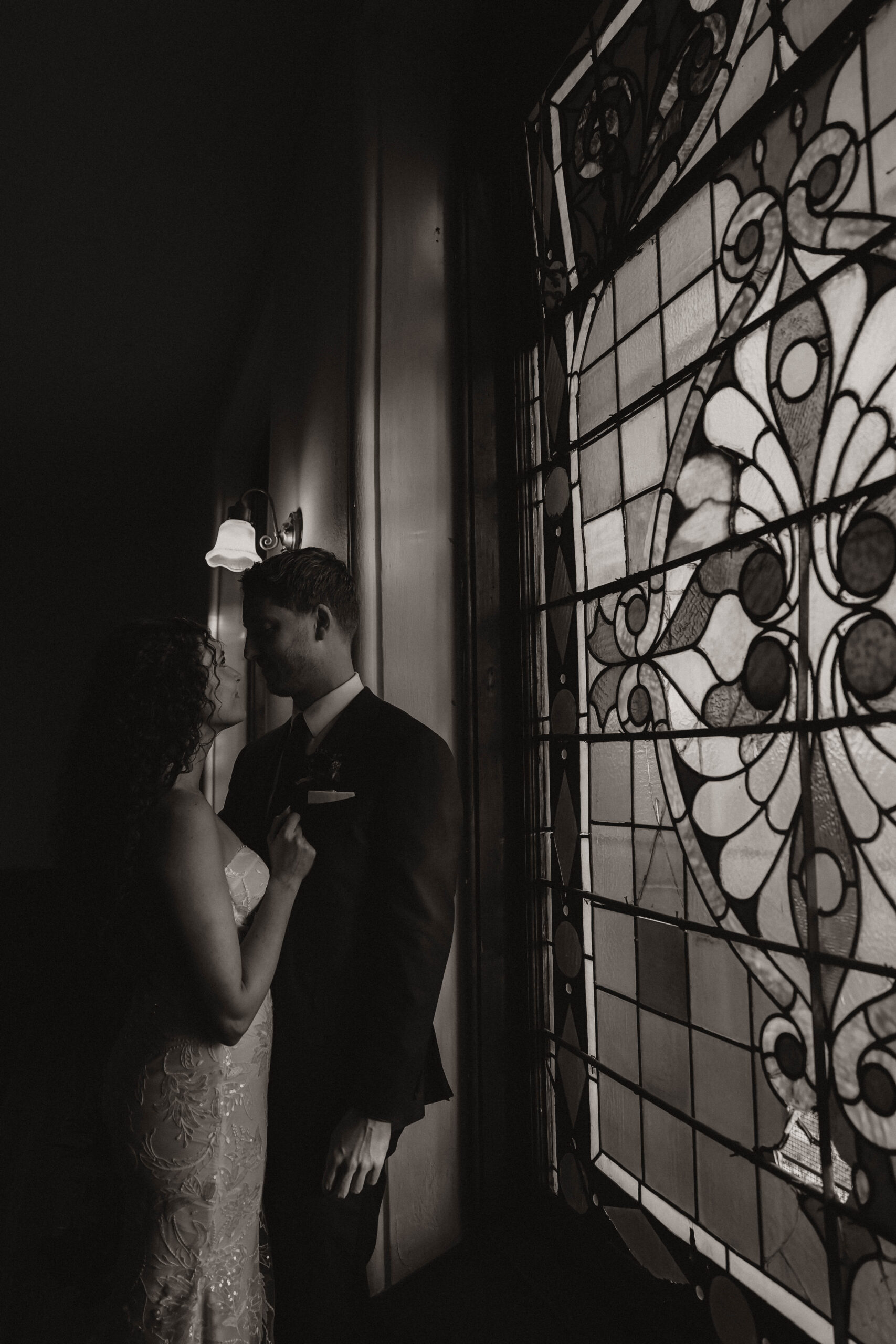 meaningful wedding moments of the bride and groom by a stained glass window 