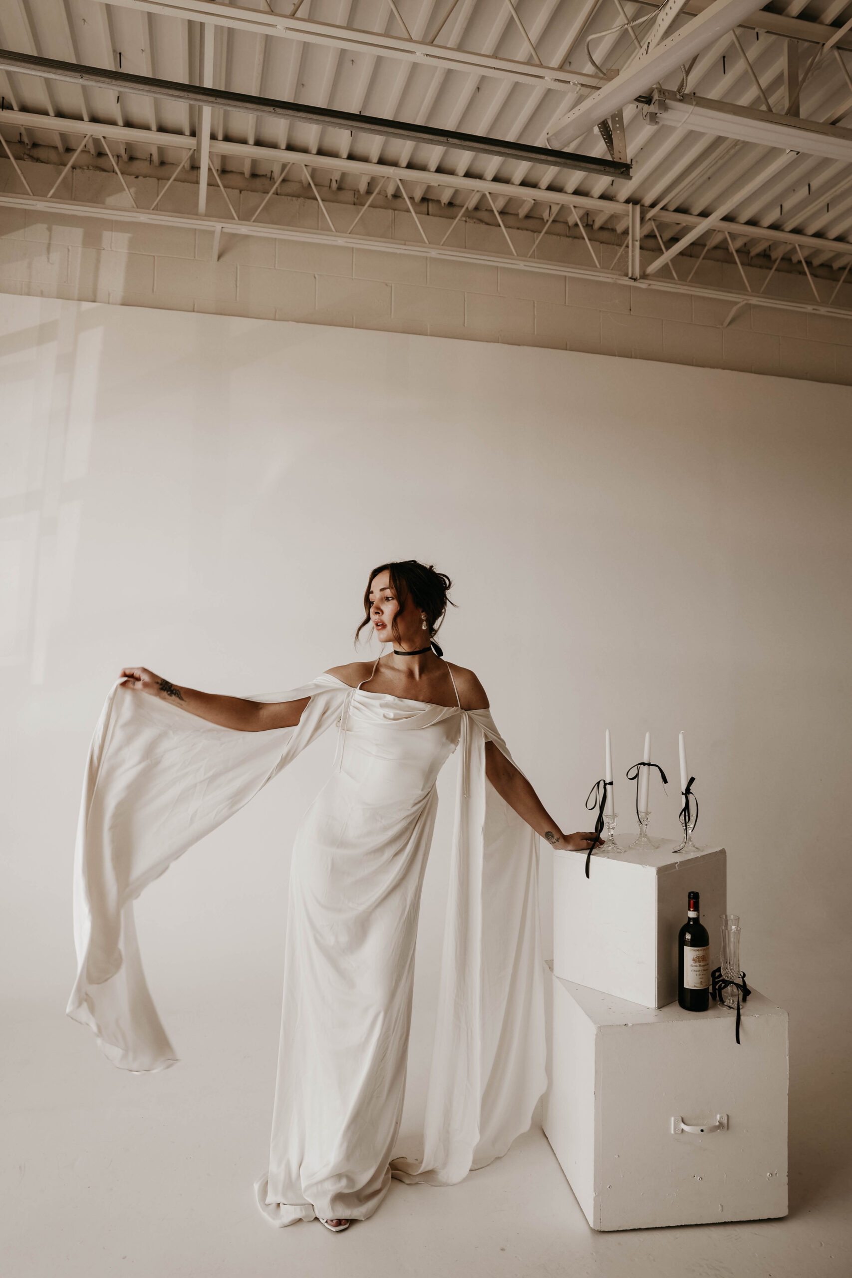 studio bridal photography of bride flowing out her sleeves while leaning on props 