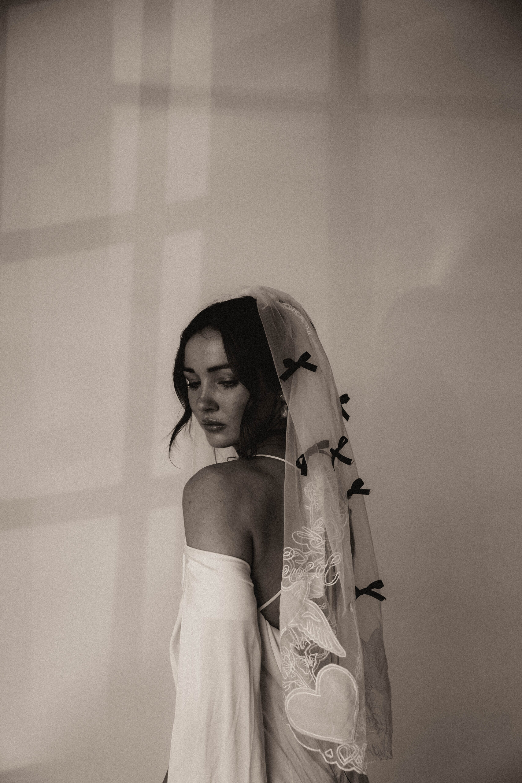 studio bridal photography of bride with veil with black bows 