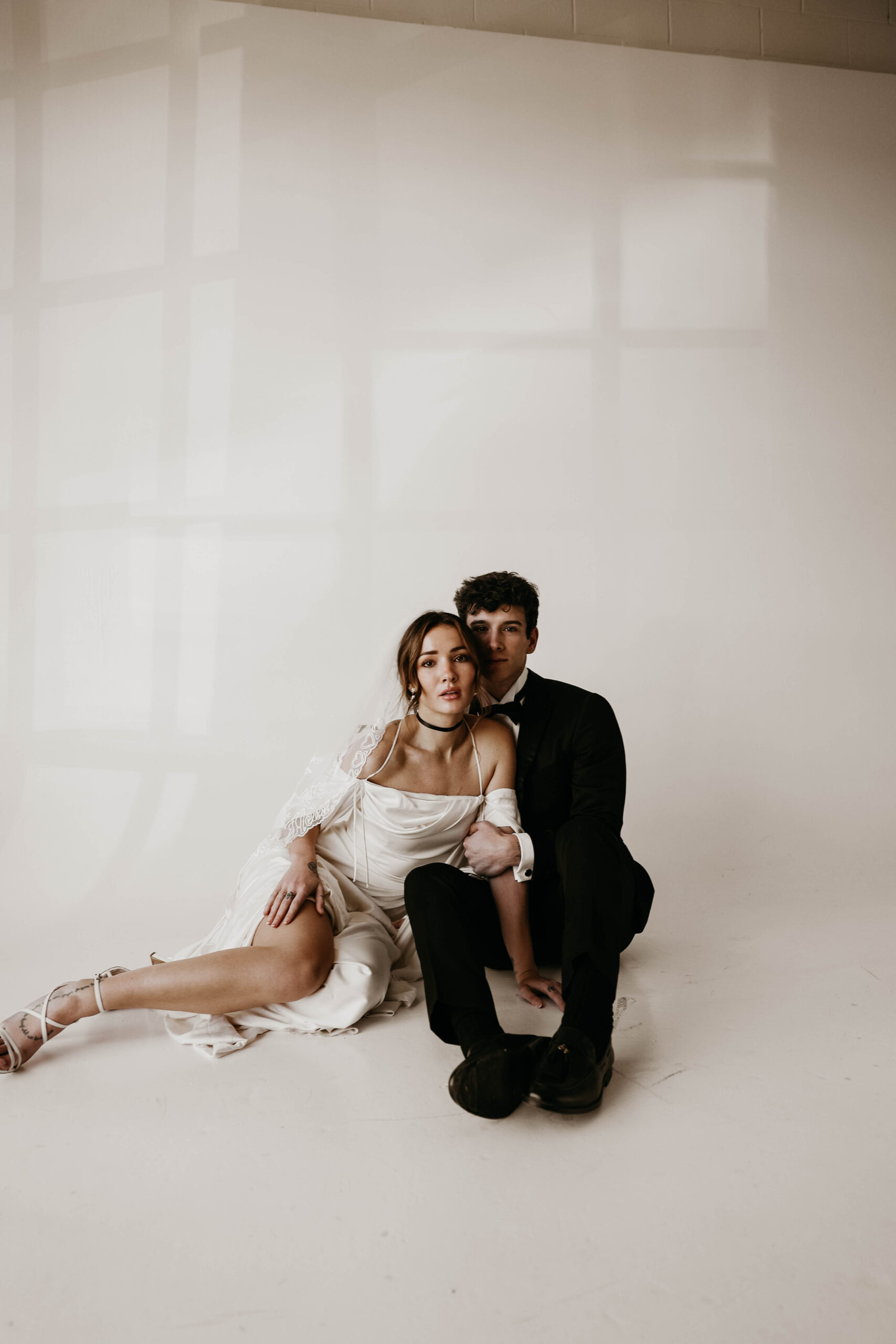 studio bridal photography of bride and groom sitting on the floor 