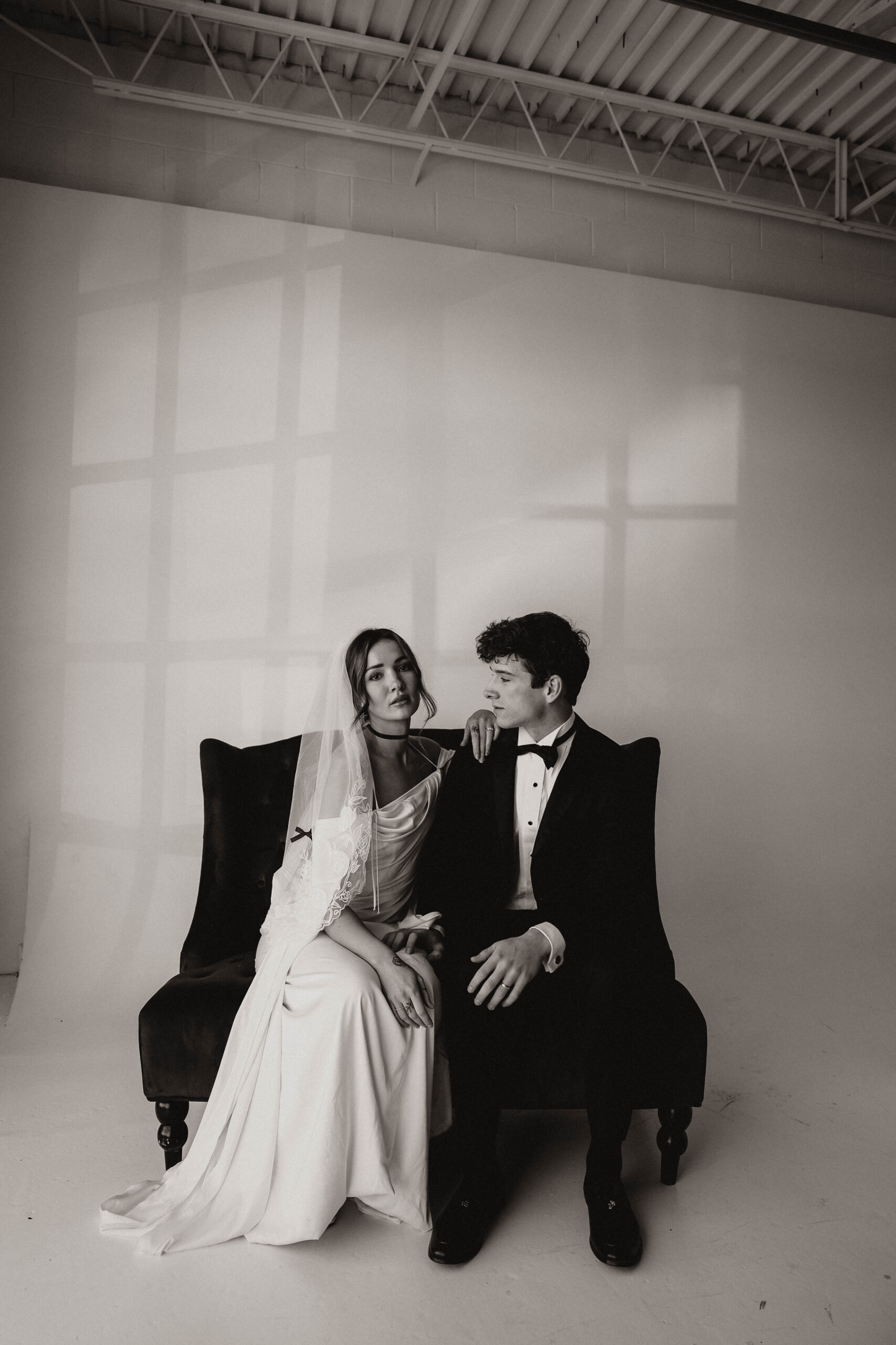 studio bridal photography of bride and groom sitting on a chair 