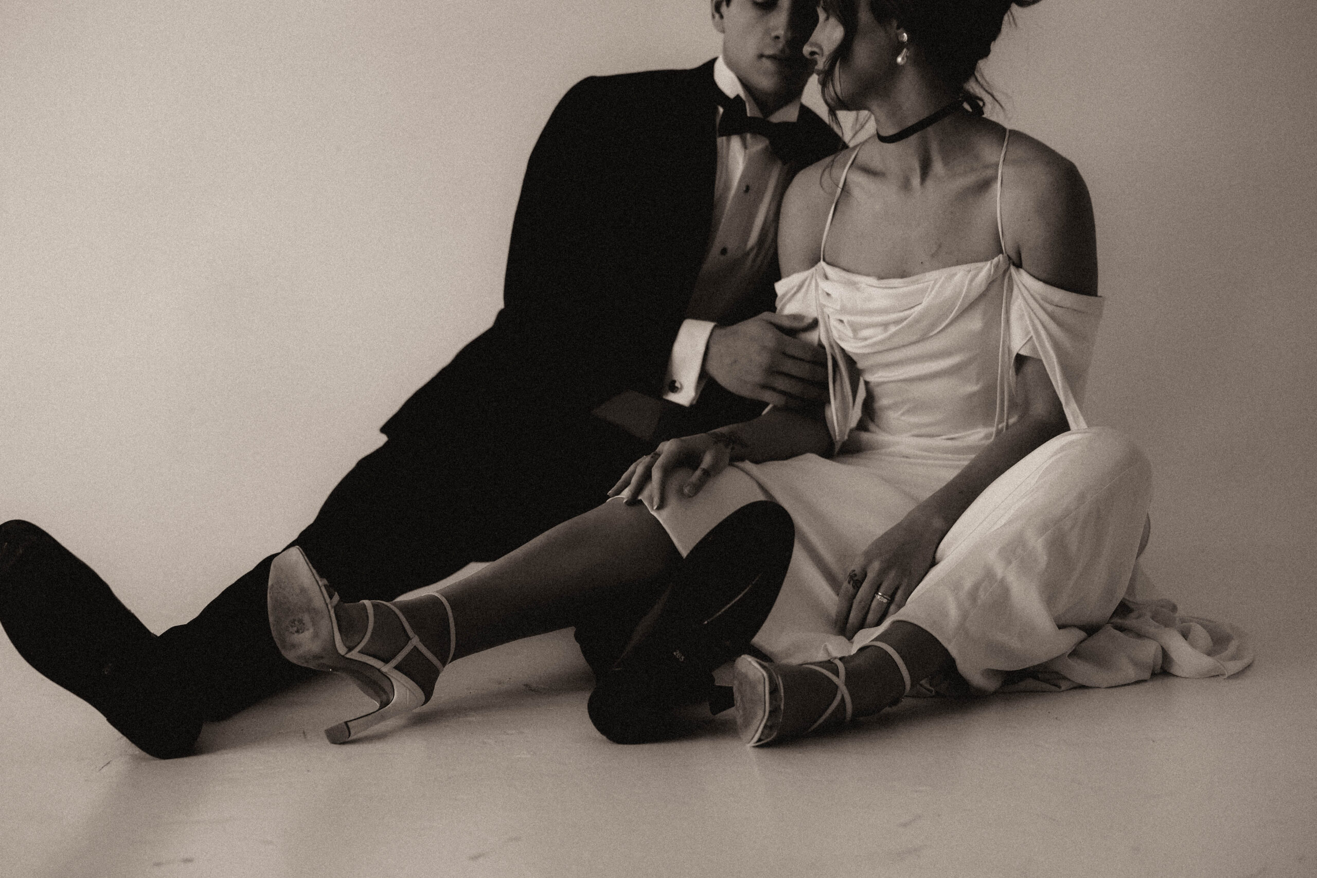 studio bridal photography of bride and groom sitting on the floor together 