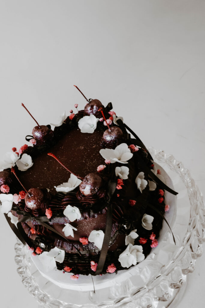 close up of chocolate cake with flowers and cherries 