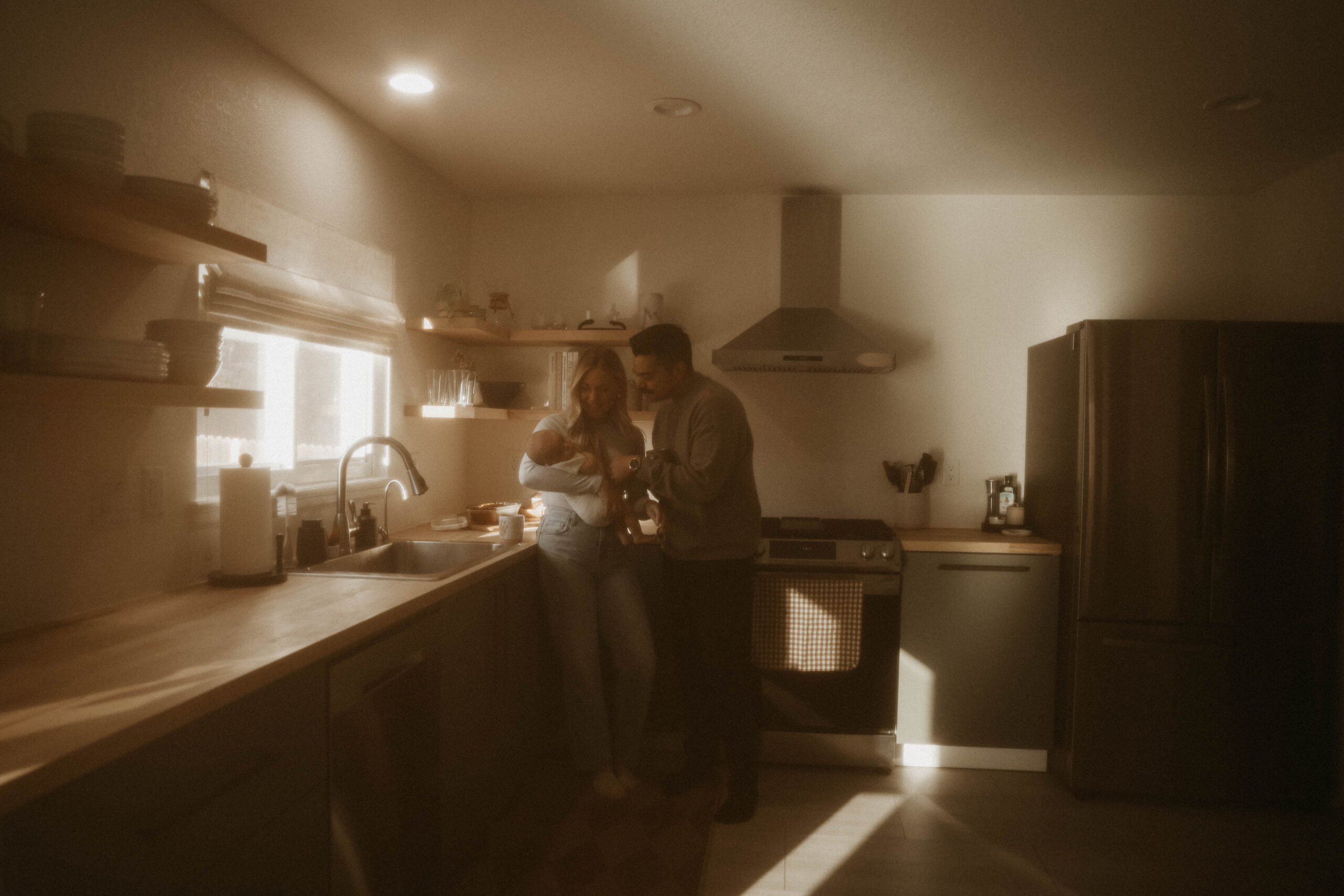 parents holding their newborn in the kitchen during in-home family photos 