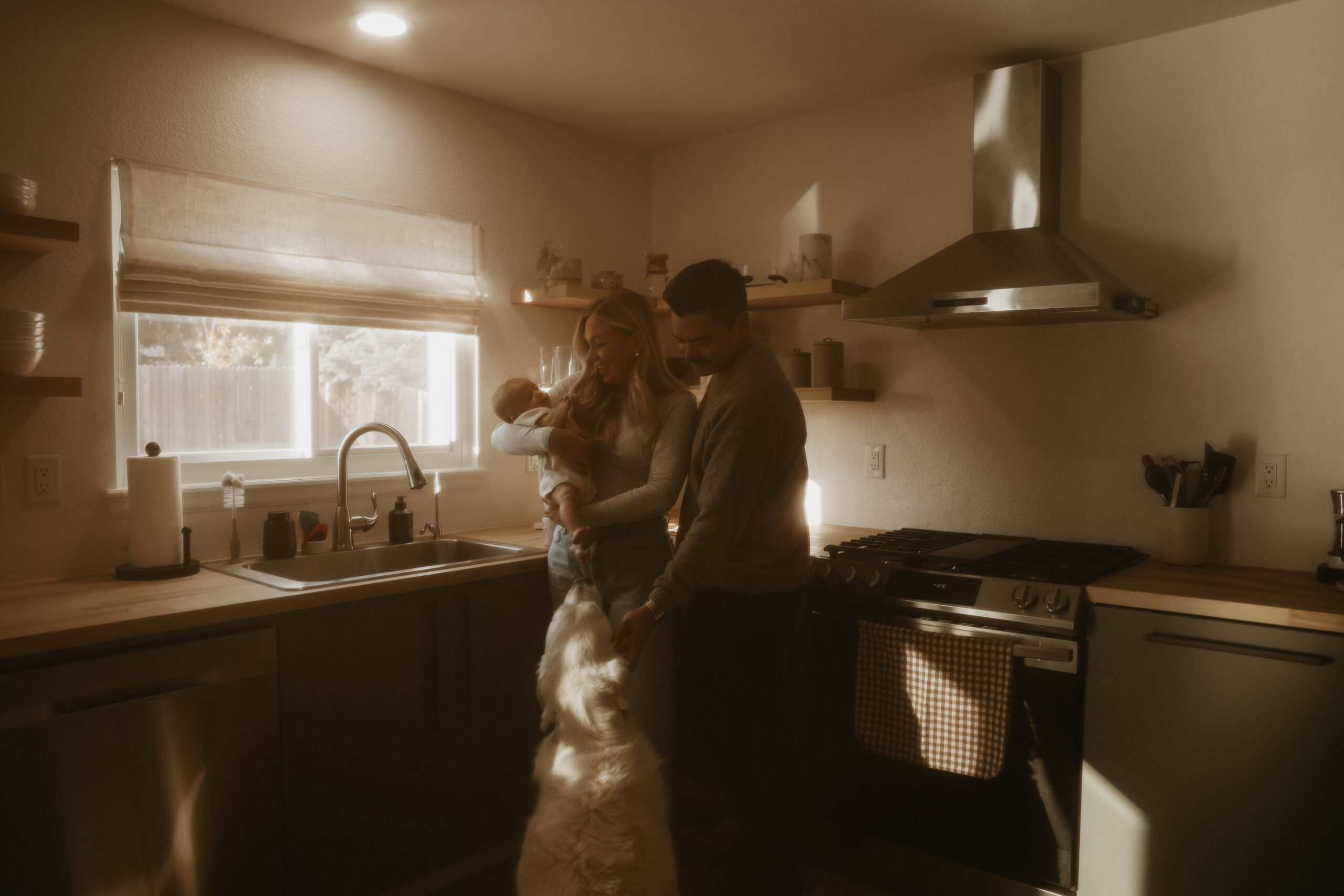 a couple in the kitchen holding their baby during in-home family photos 
