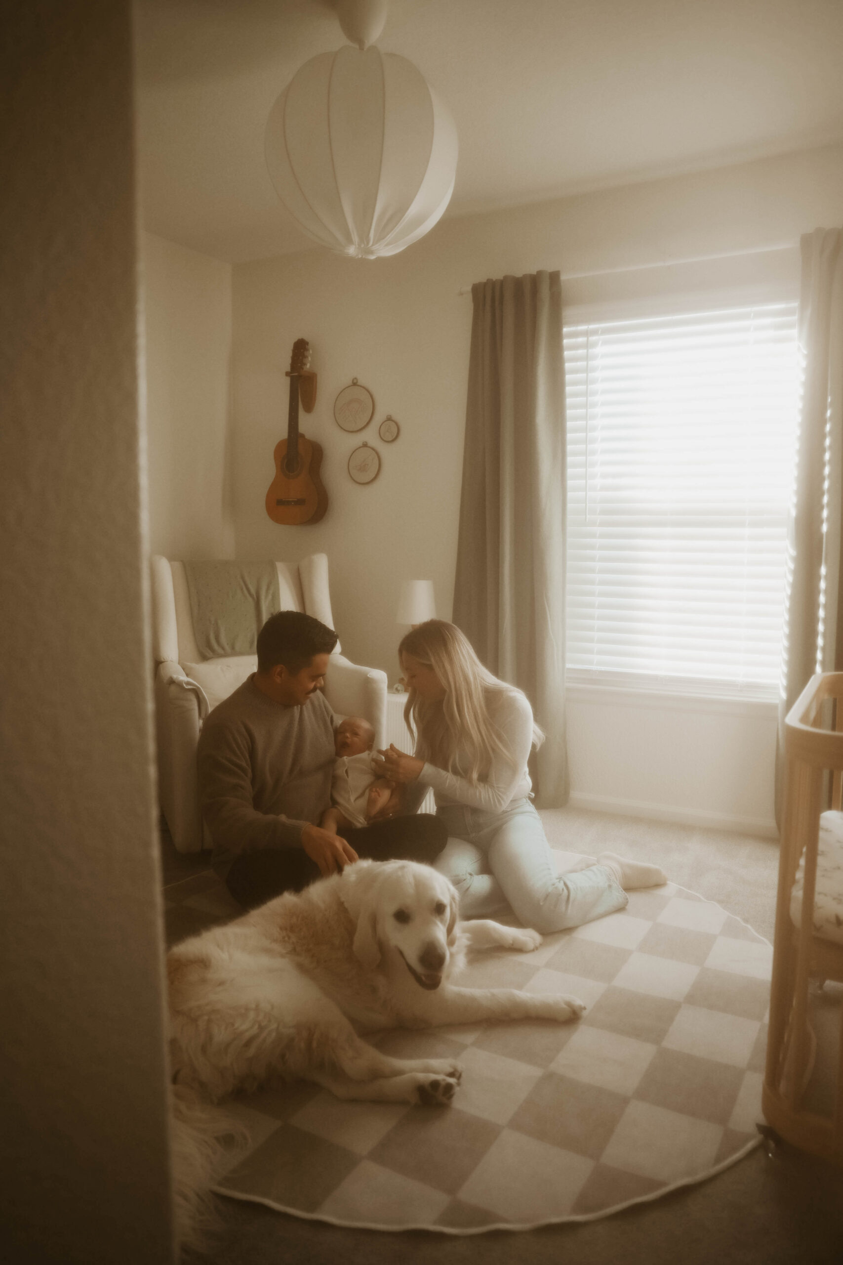a family sitting on the nursery floor with their dog during in-home family photos 