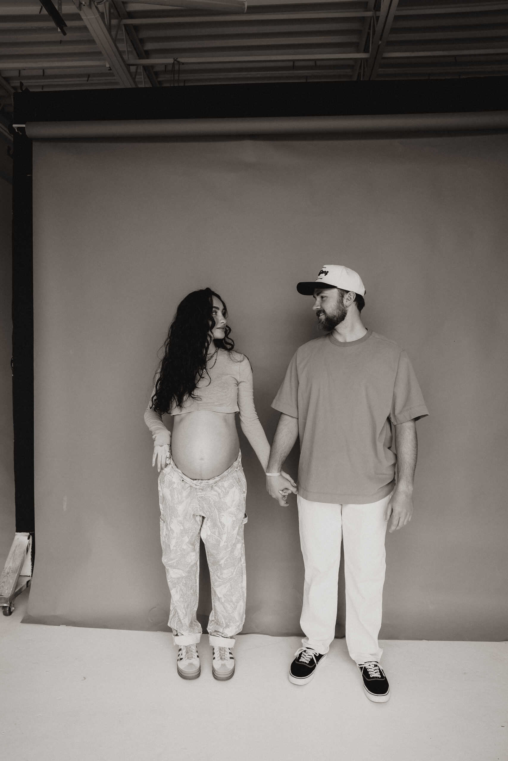 soon to be parents holding hands and looking at each other during denver maternity photoshoot