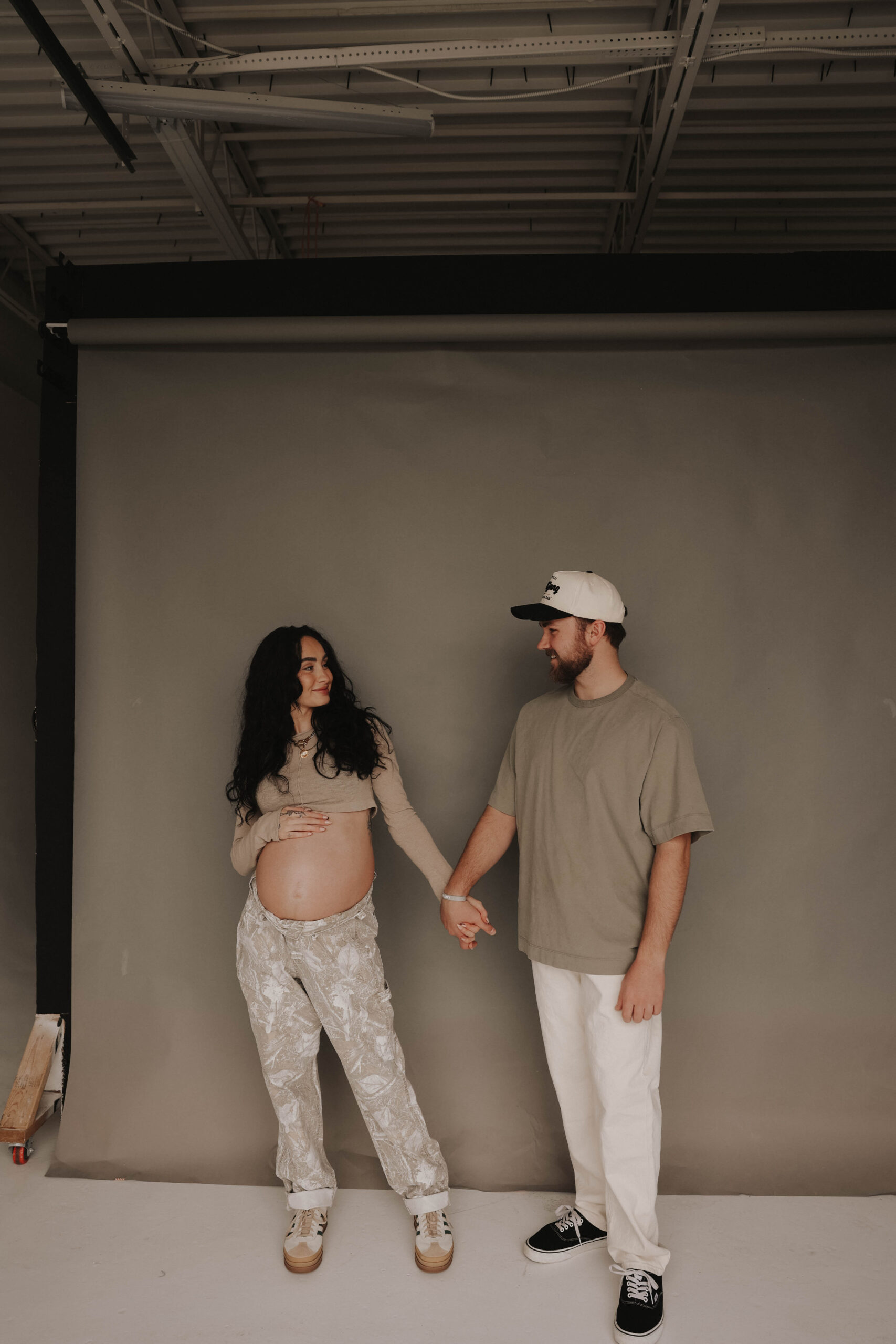 couple holding hands and looking at each other during denver maternity photoshoot