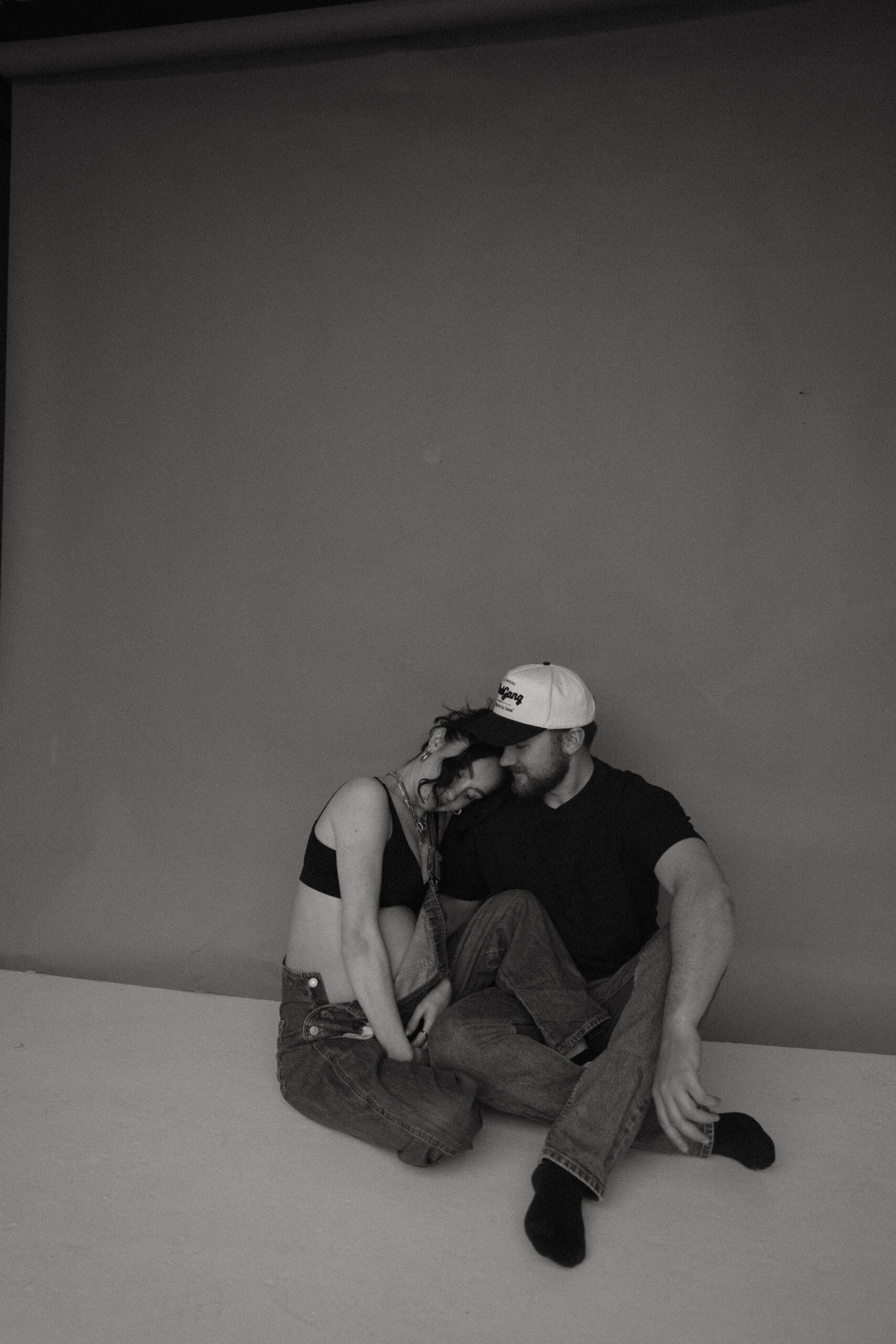 couple sitting on the floor in studio during denver maternity photoshoot