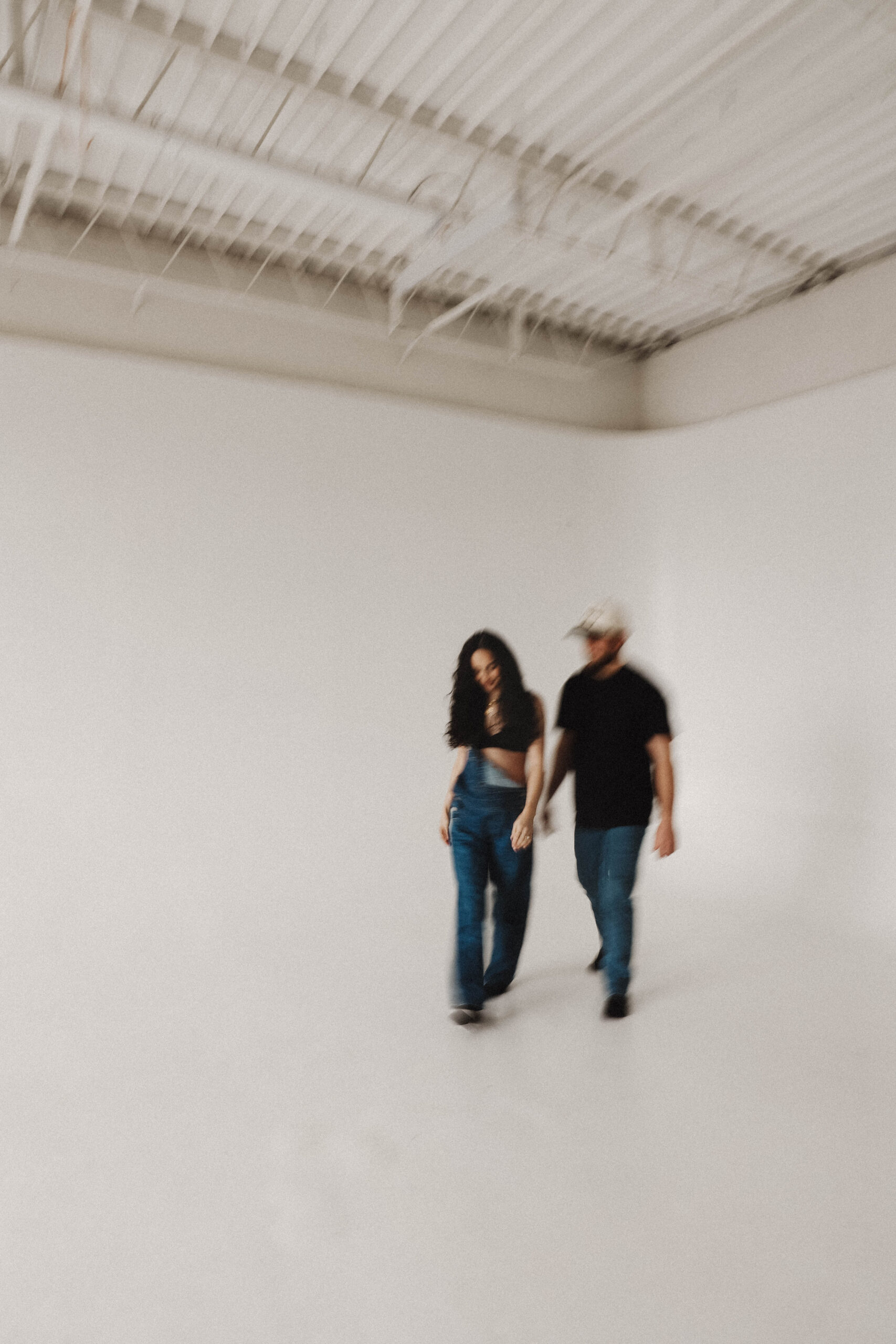 blurry image of soon to be parents holding hands and walking in the studio