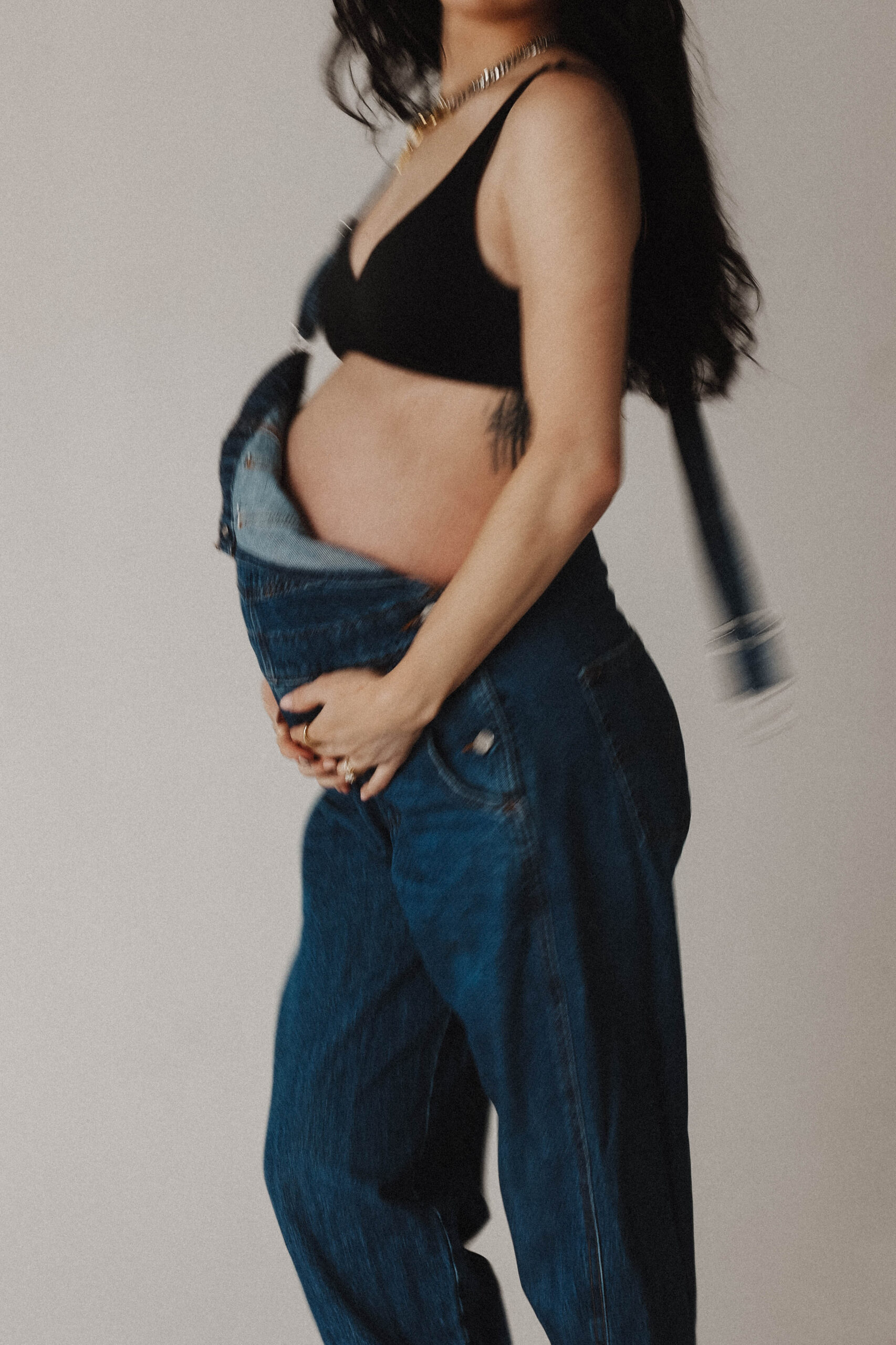 pregnant woman in overalls with a focus on her belly 