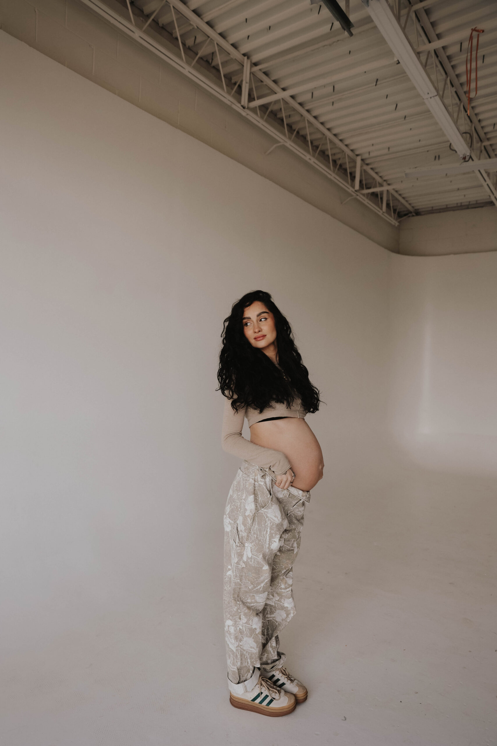 pregnant woman standing in a white studio during denver maternity photoshoot
