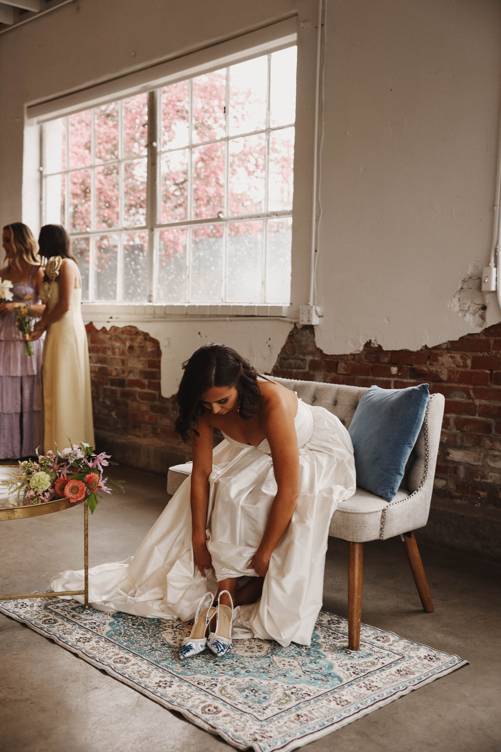 a bride sitting and putting her shoes on during a colorful spring wedding 