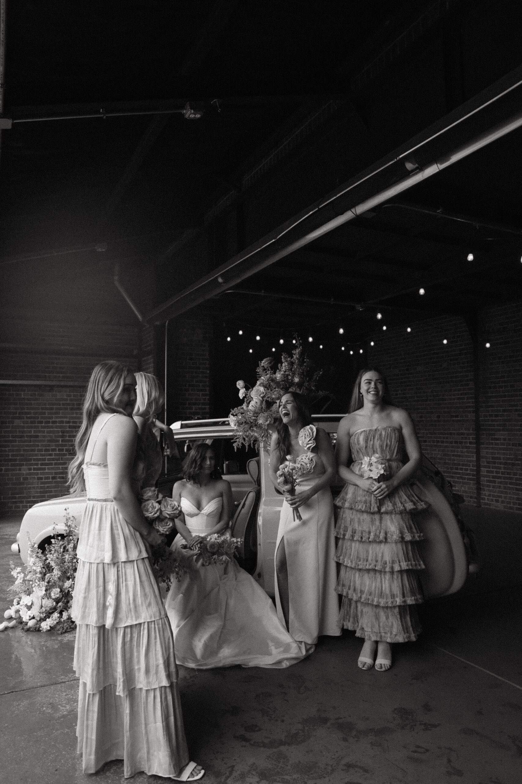 candid photo of bride and bridesmaids by floral car